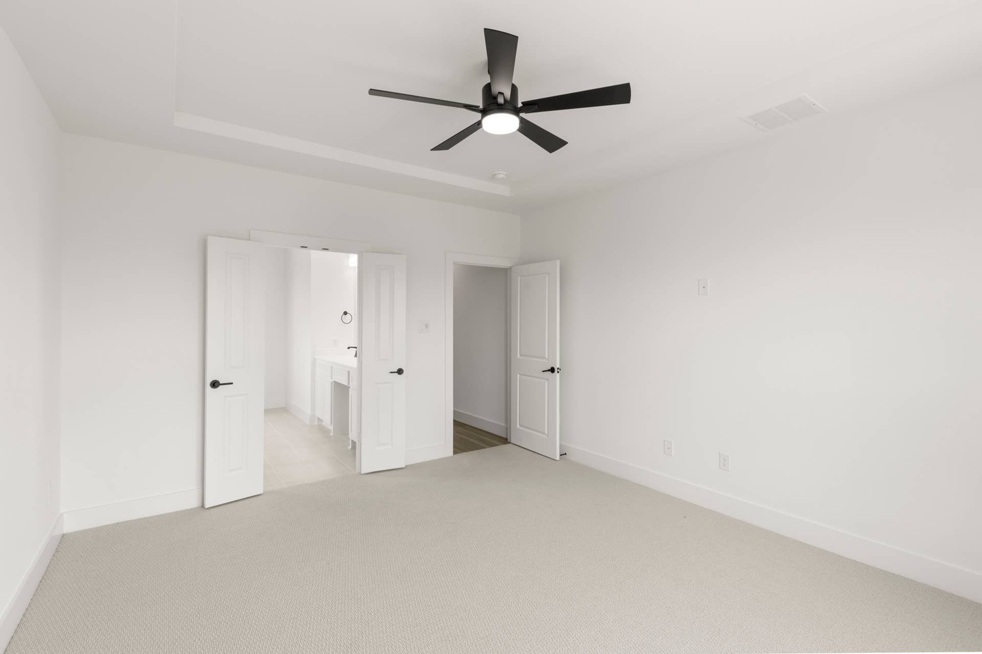 Spacious primary bedroom with ceiling fan and ensuite bathroom access.