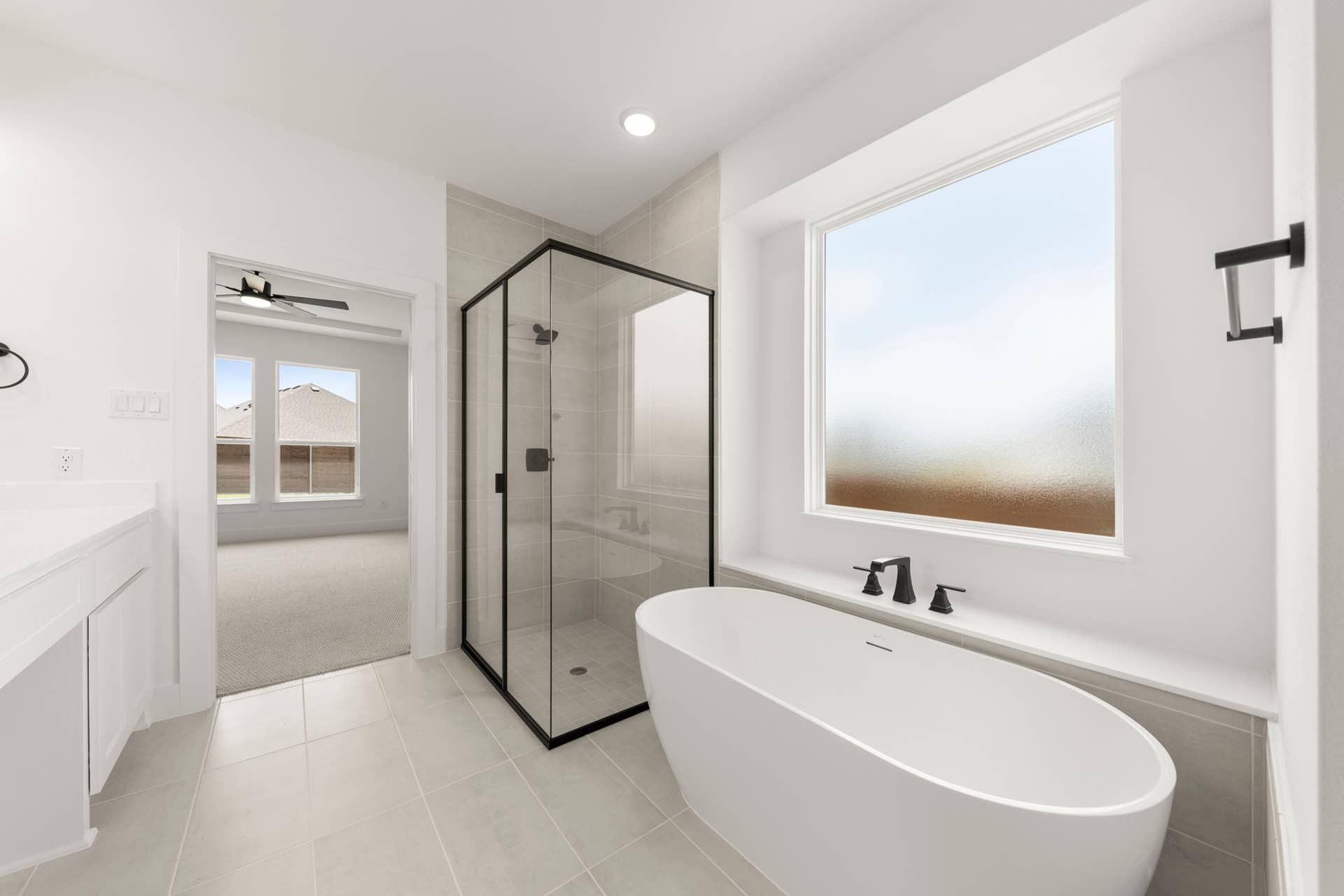 Modern bathroom with freestanding tub, glass shower, and large frosted window.