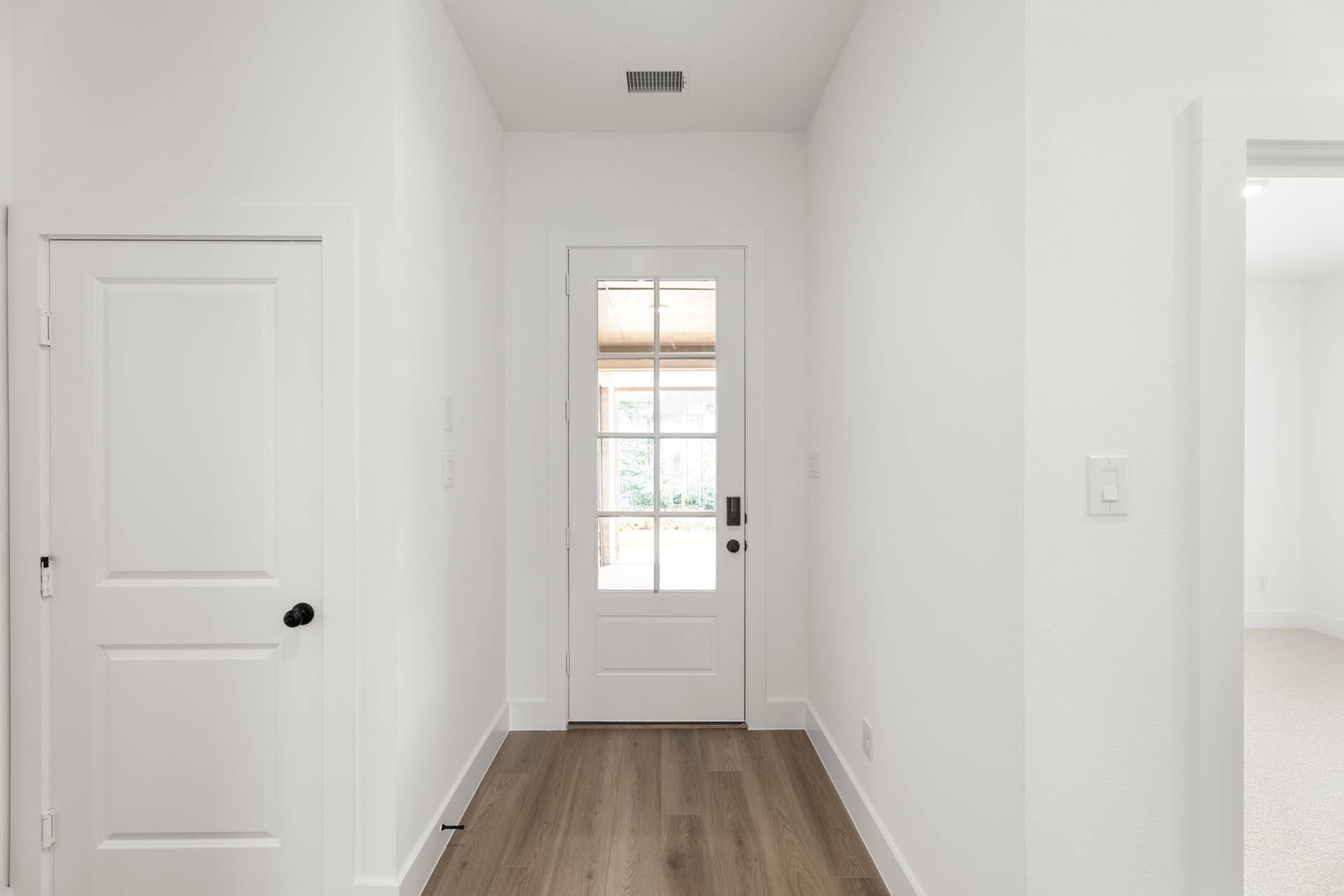 Bright entryway with wooden flooring and glass panel door.