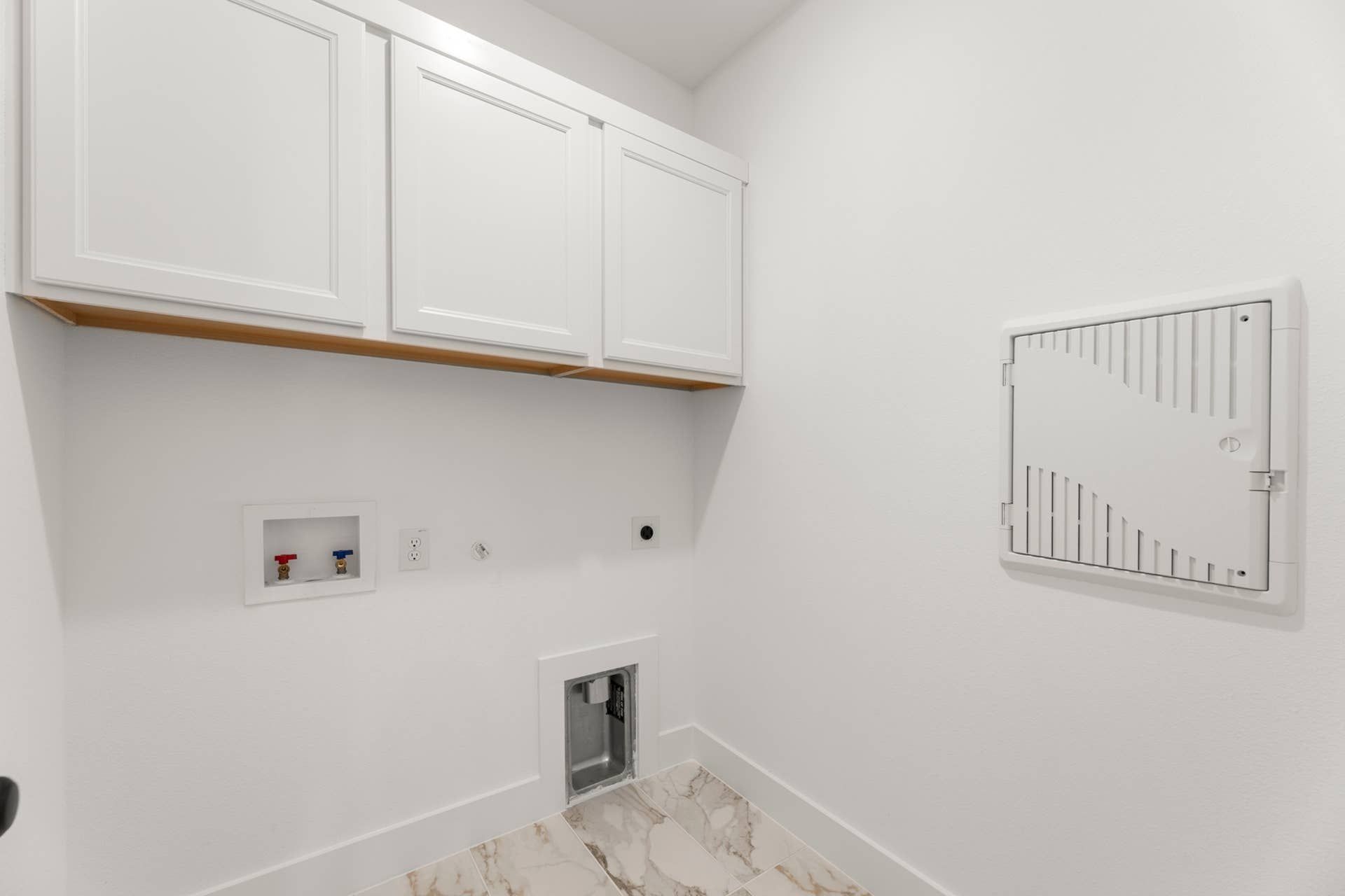 Laundry utility room with white cabinets and plumbing hookups.