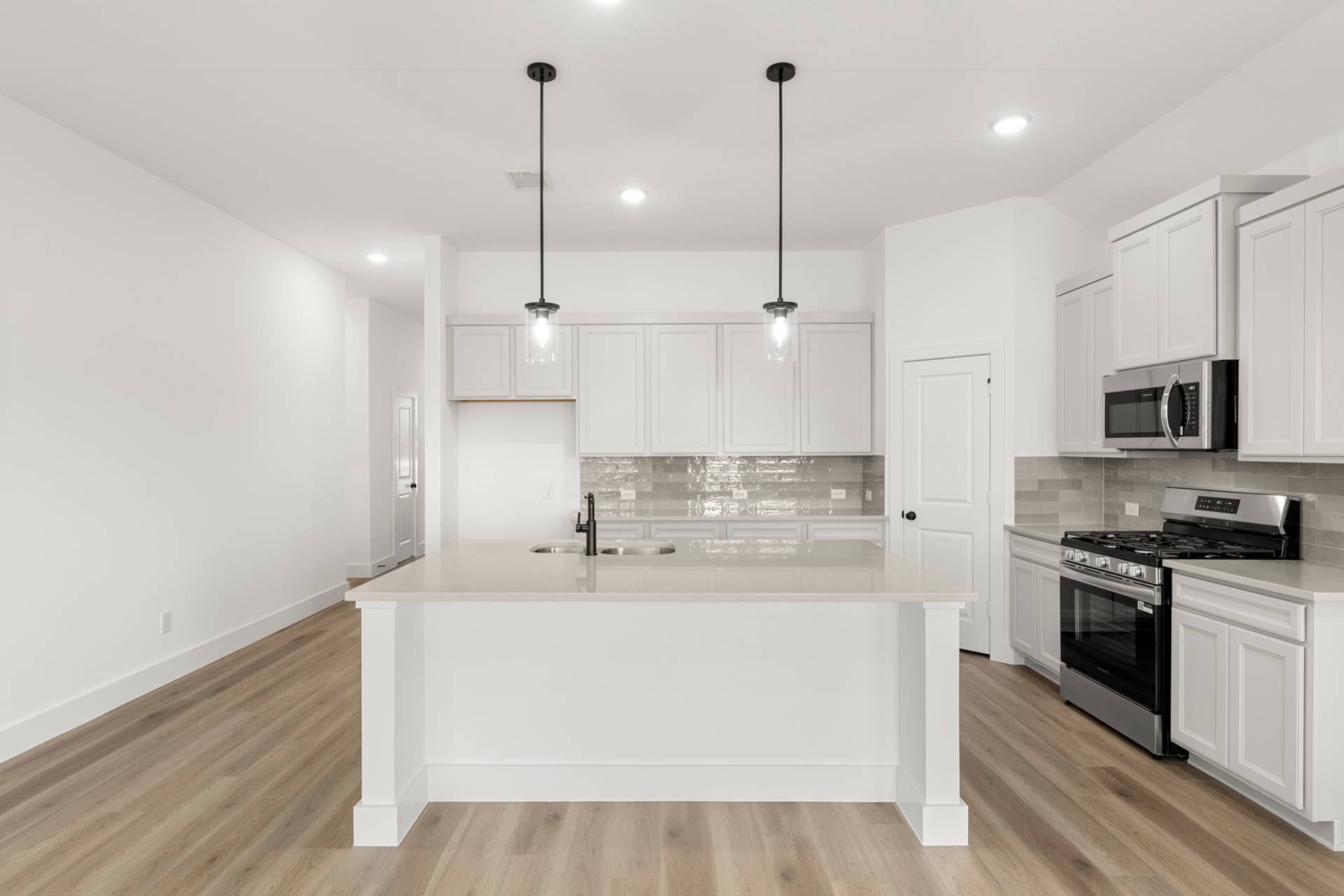 Modern kitchen with white cabinets, island, and stainless steel appliances.