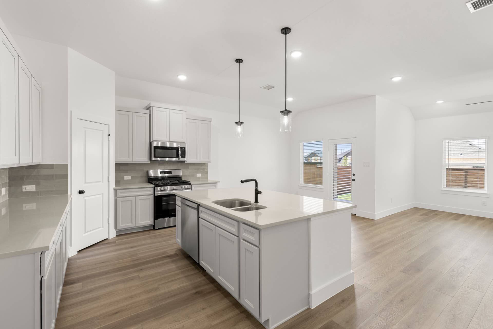 Modern kitchen with island, pendant lighting, and stainless steel appliances.