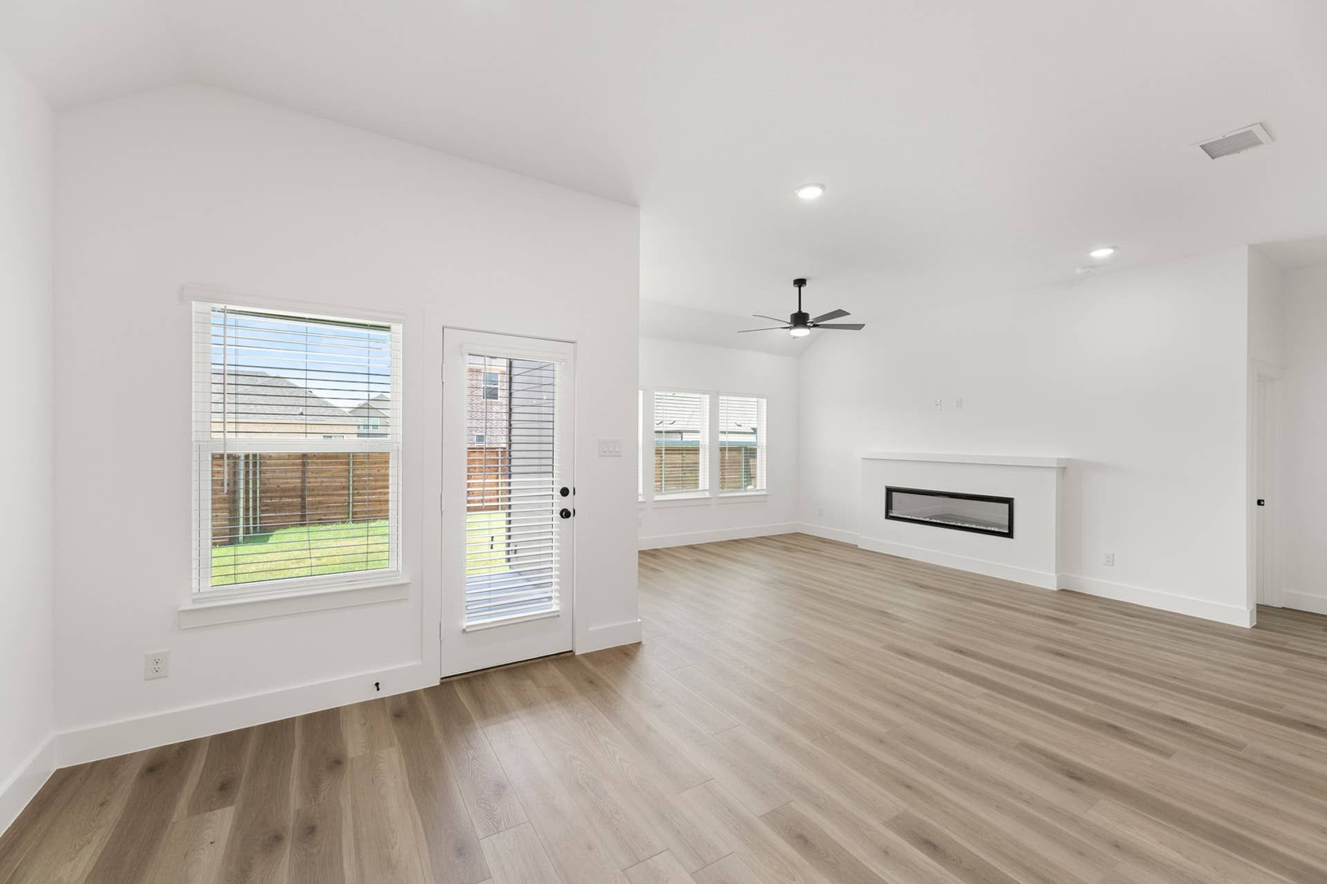 Spacious dining area with large windows, modern ceiling fan, and sleek fireplace.