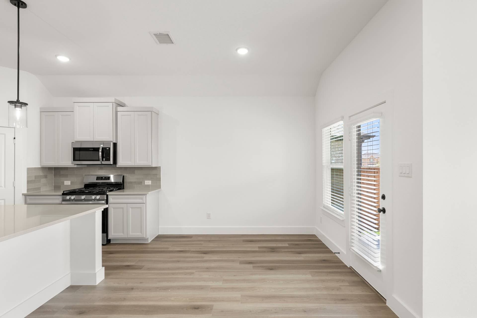 Modern kitchen and dining area with white cabinetry and hardwood floors.