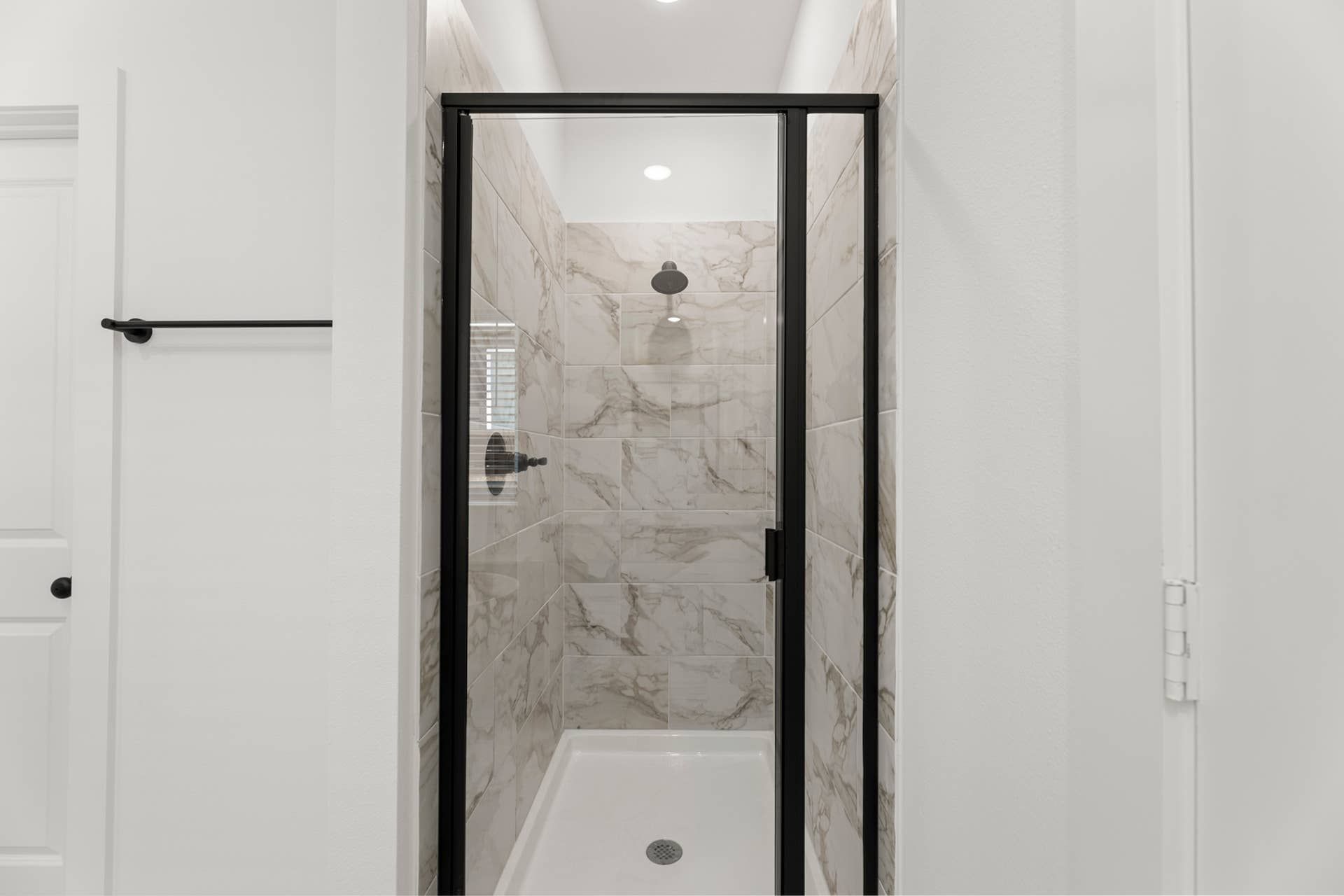 Modern bathroom shower with marble tiles and glass door.