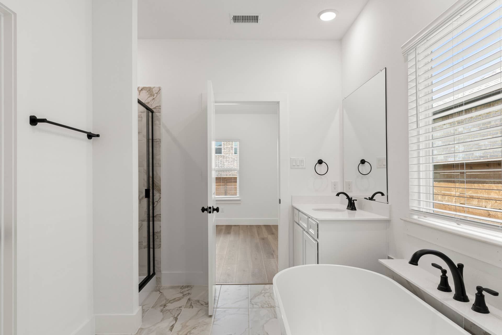 Modern bathroom with freestanding tub, marble tiles, and black fixtures.