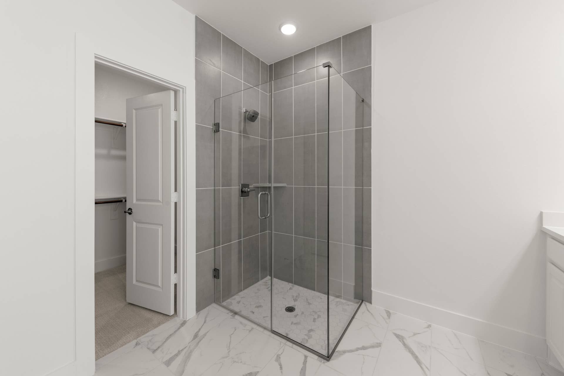 Modern bathroom with glass shower and marble floor tiles.