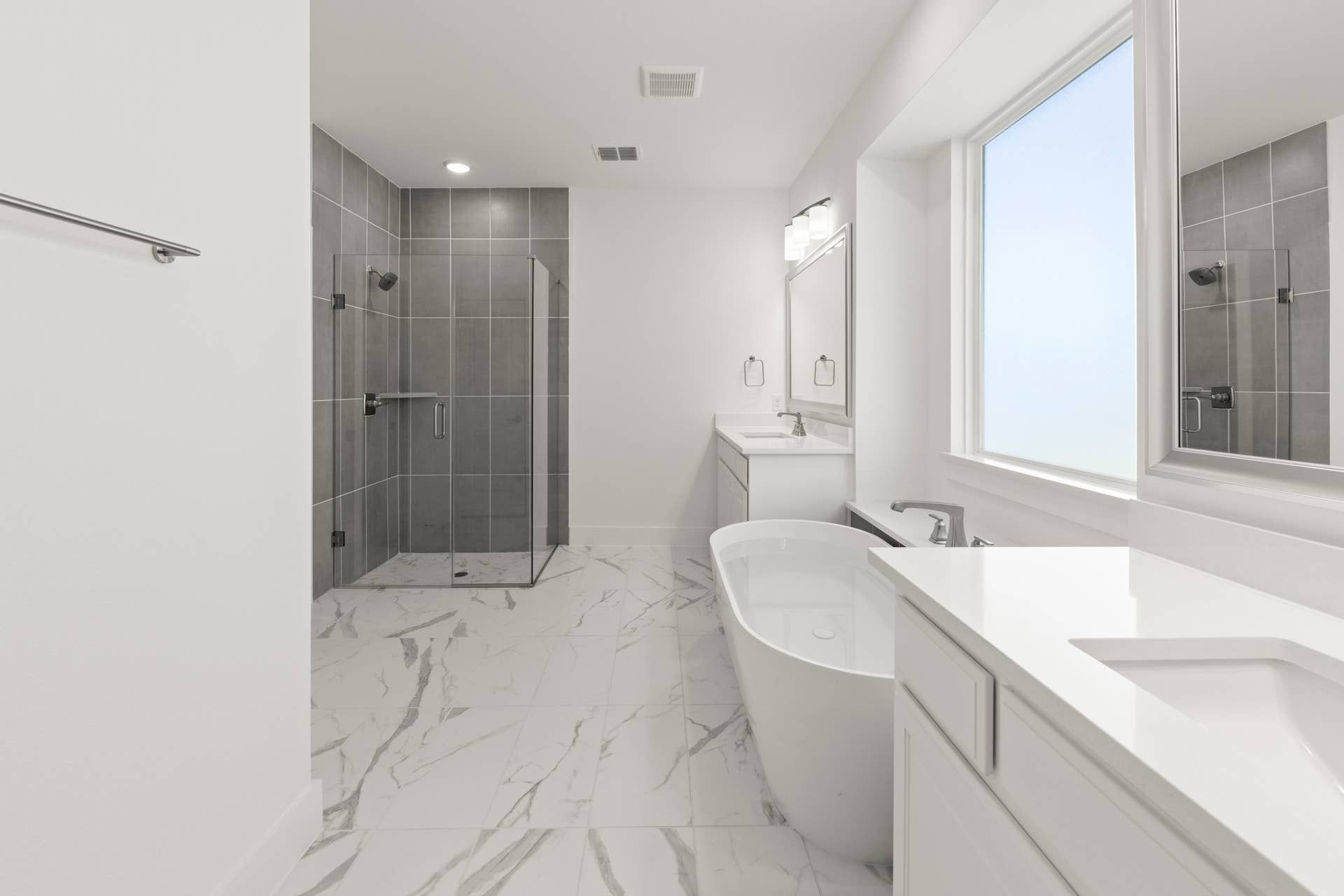 Modern bathroom with freestanding tub, glass shower, and marble tile flooring.
