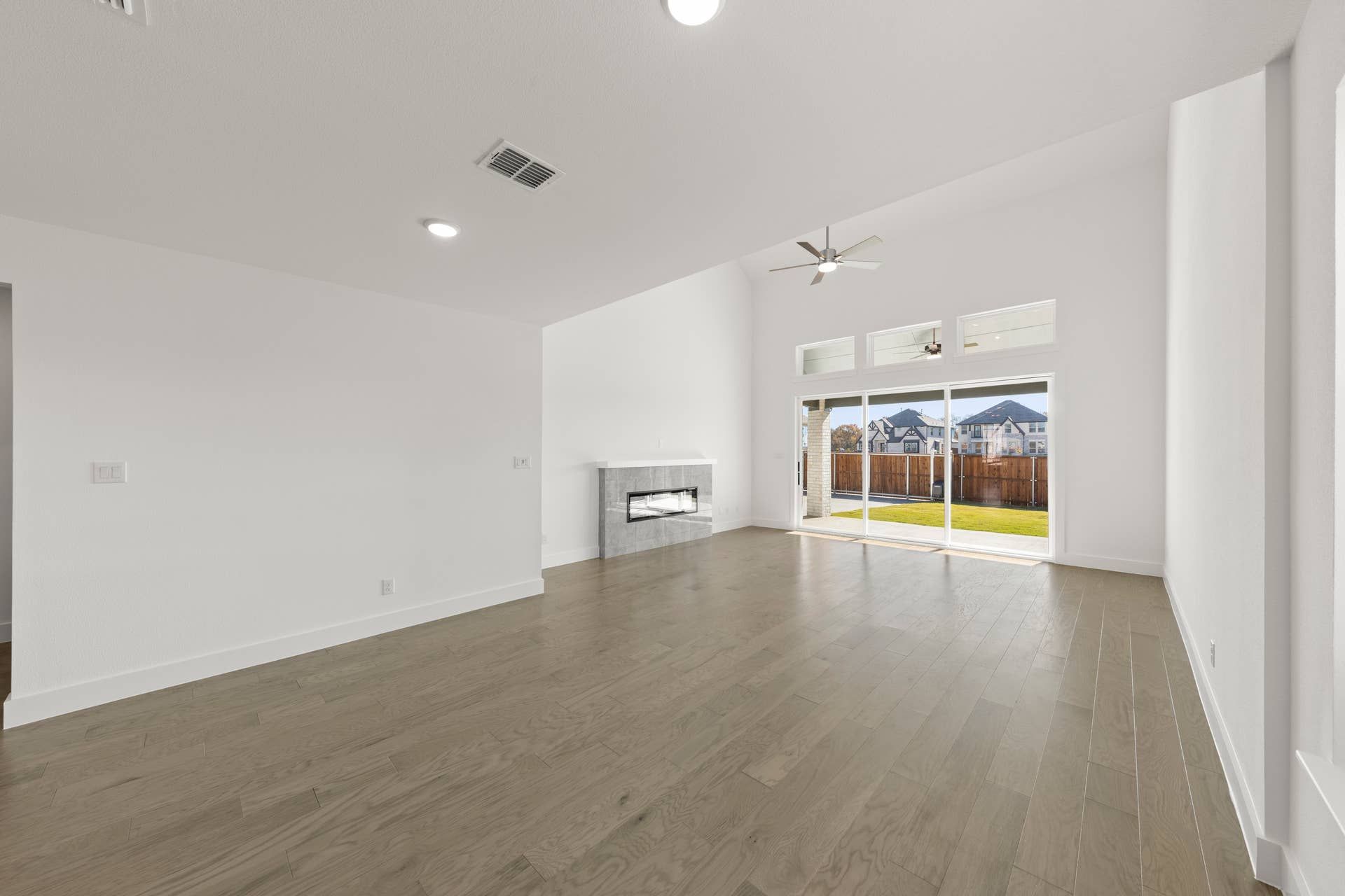 Spacious living room with hardwood floors, fireplace, and large windows overlooking backyard.