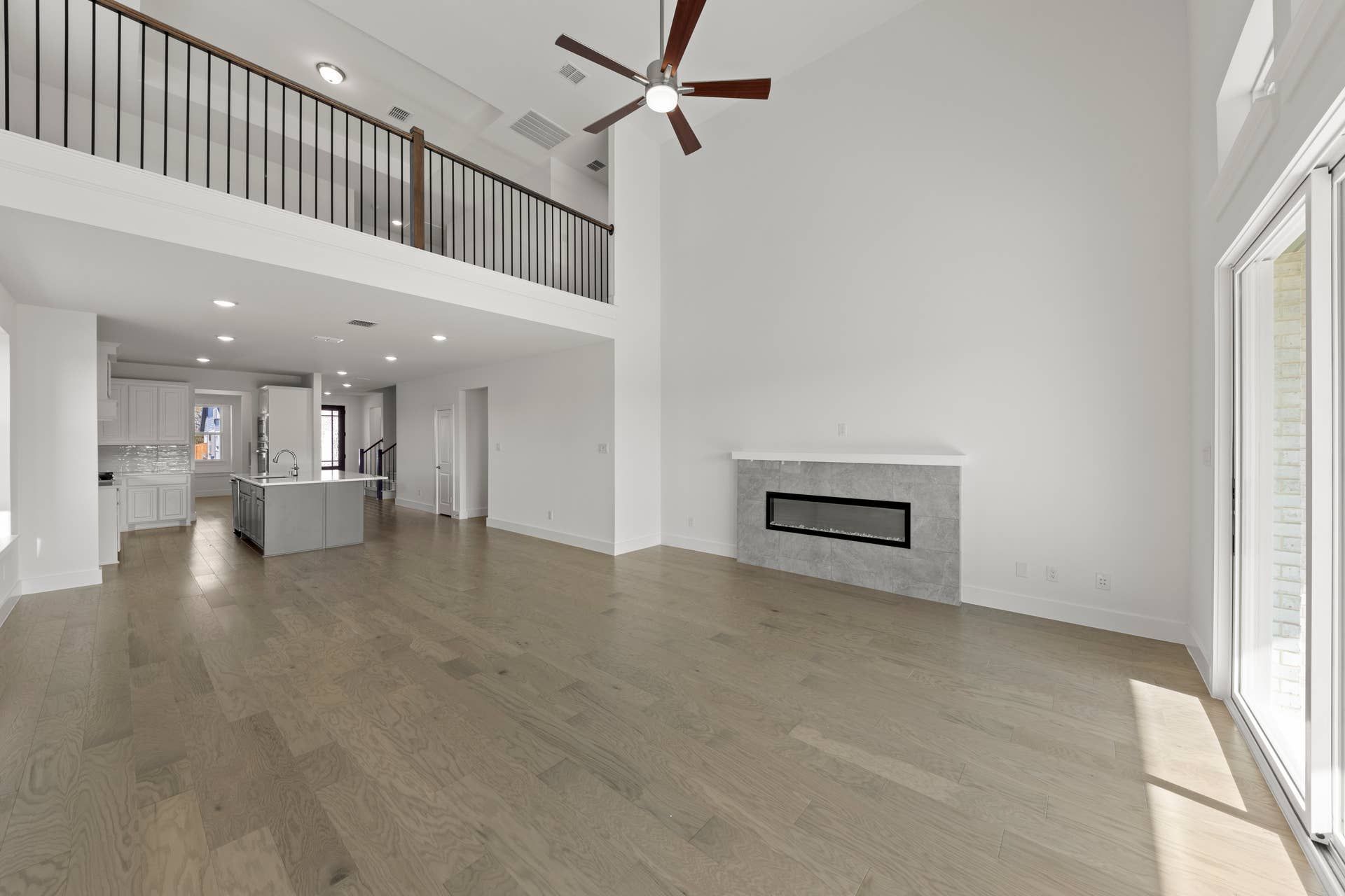Spacious open-concept interior with modern fireplace and loft view.