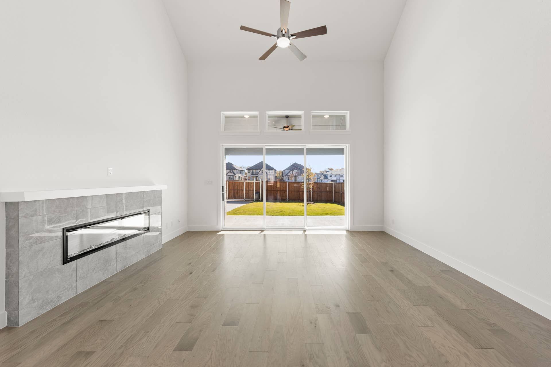 Spacious living room with modern fireplace and large windows overlooking backyard.