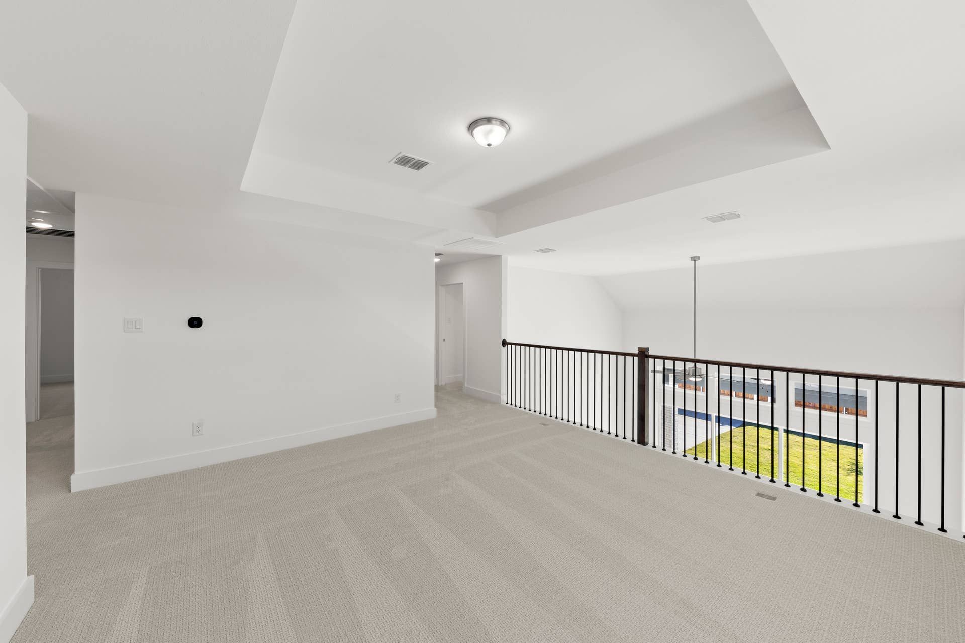 Spacious, carpeted loft area with railing overlooking lower level and natural light.