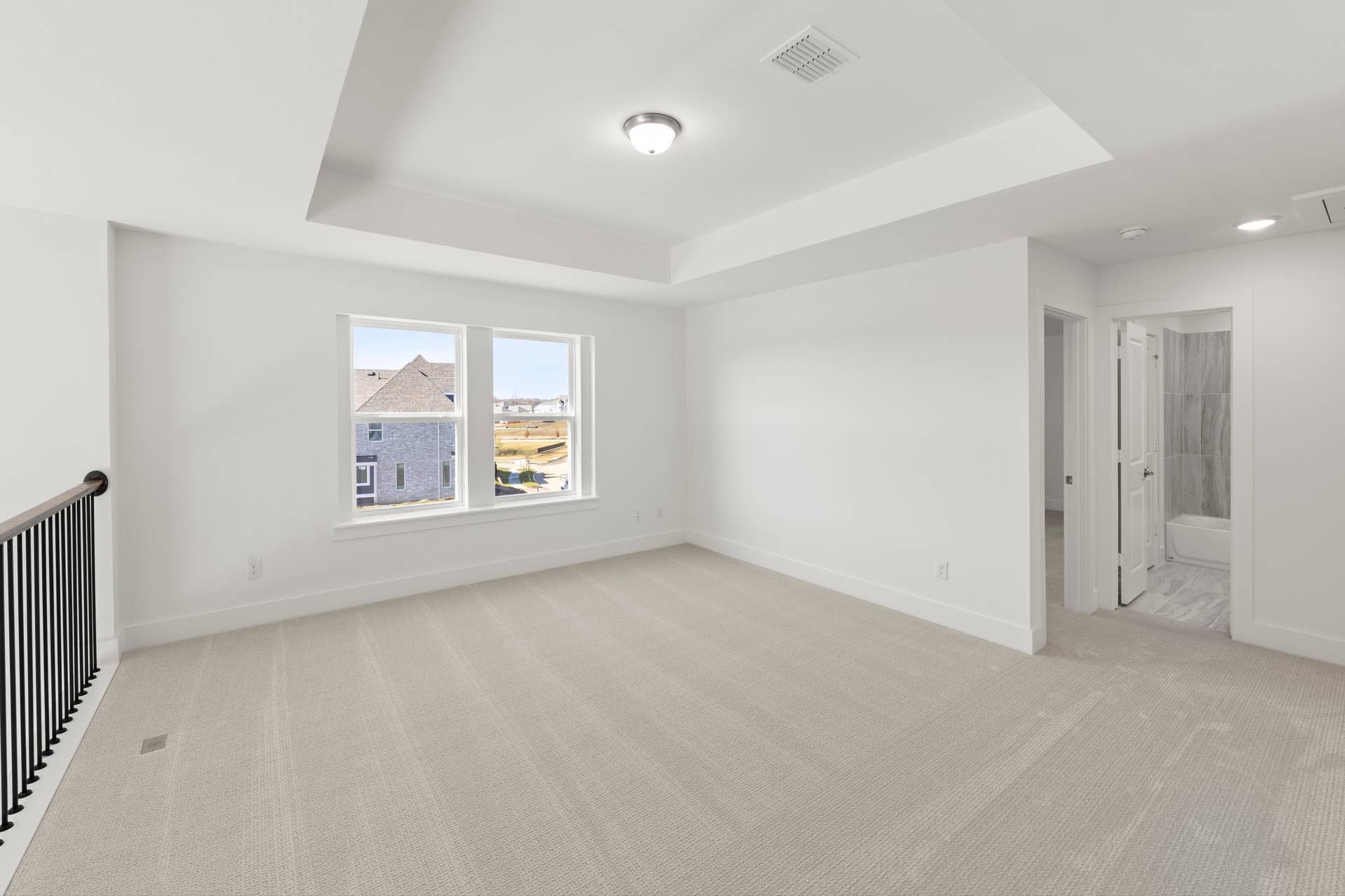 Spacious neutral-toned room with large windows and adjacent bathroom.