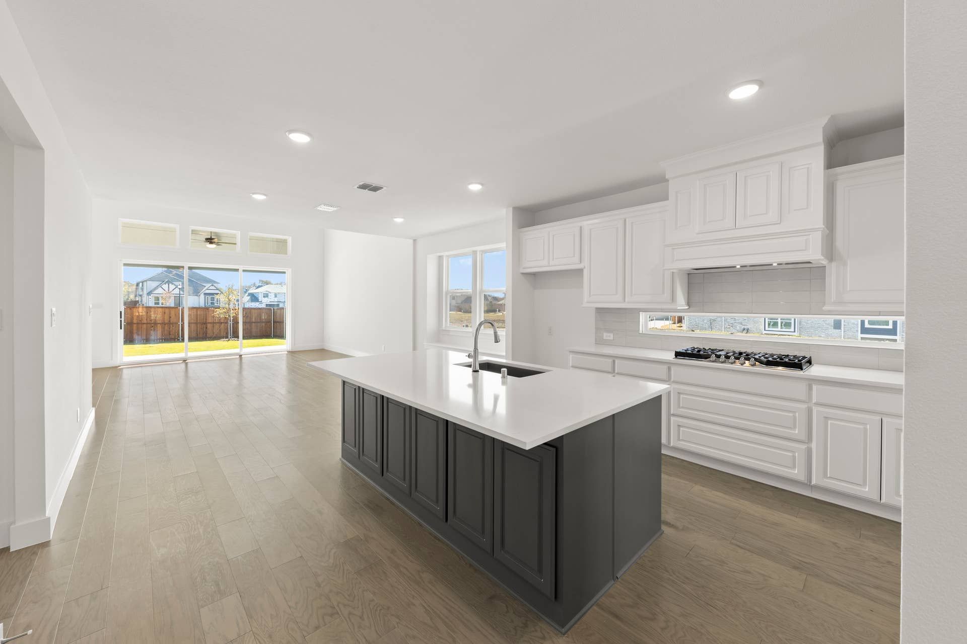 Spacious kitchen with large island, white cabinetry, and wood flooring.