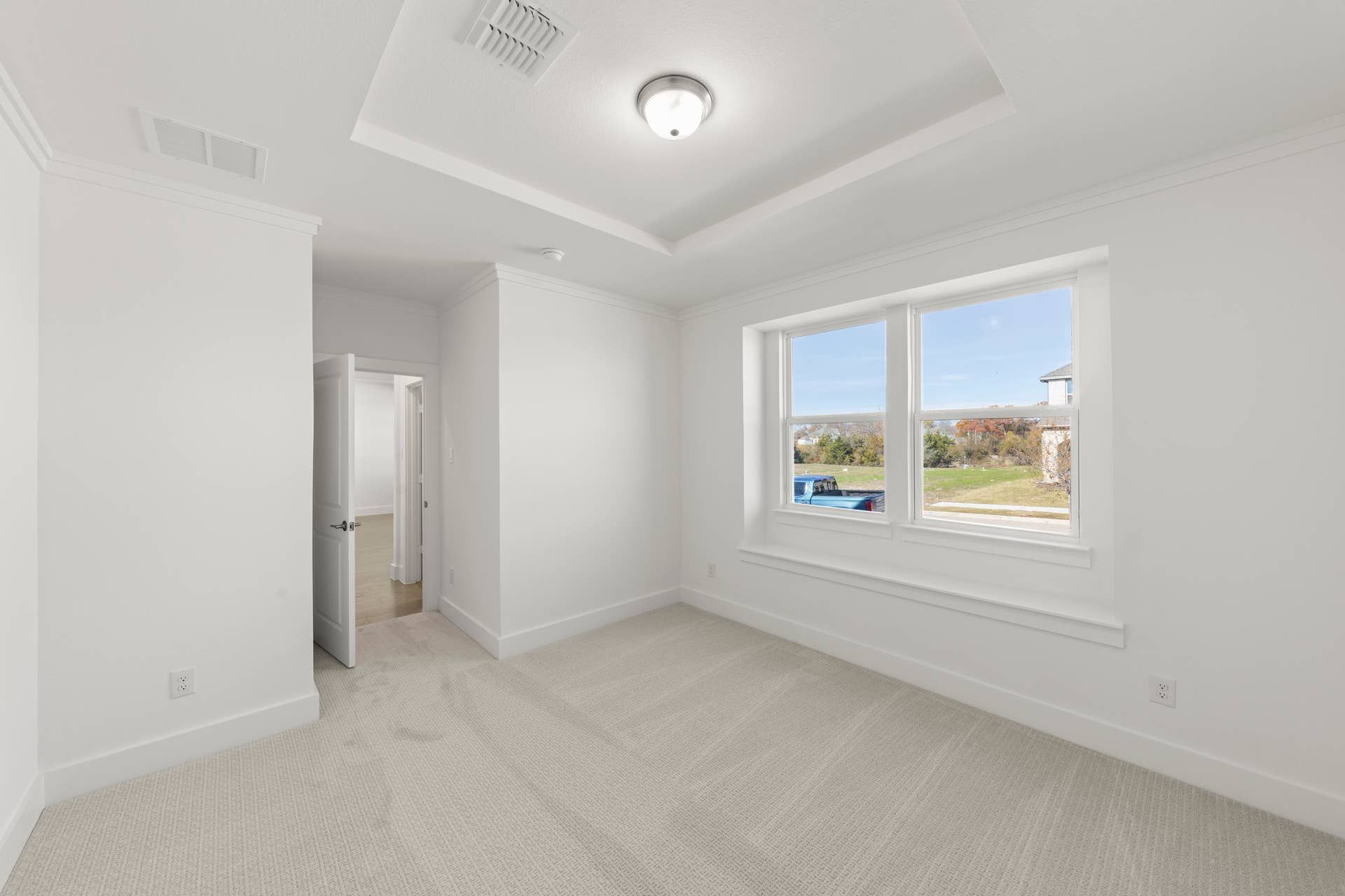 Bright study room with large window and neutral carpeting.