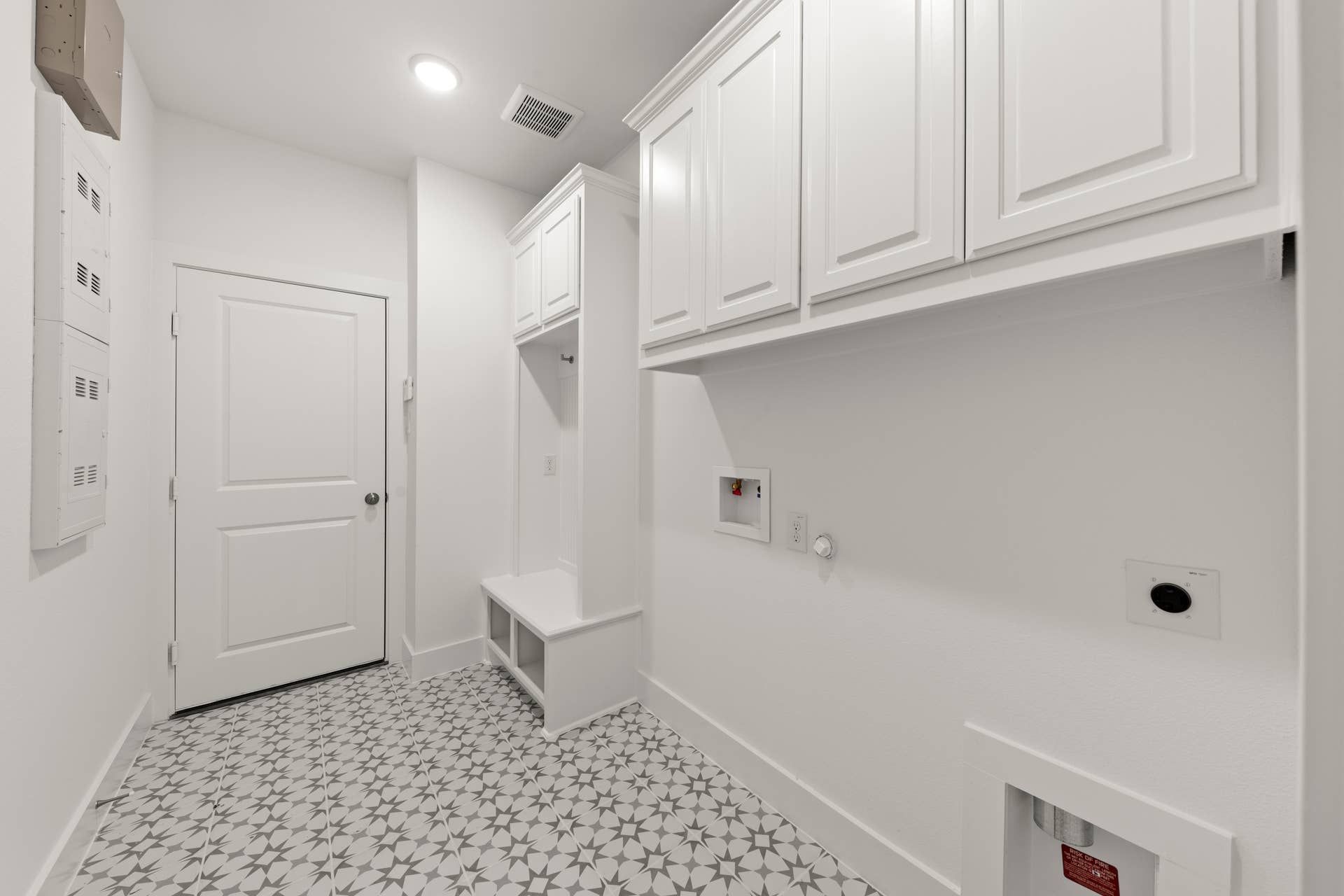 Modern utility room with patterned tile floor and white cabinetry.