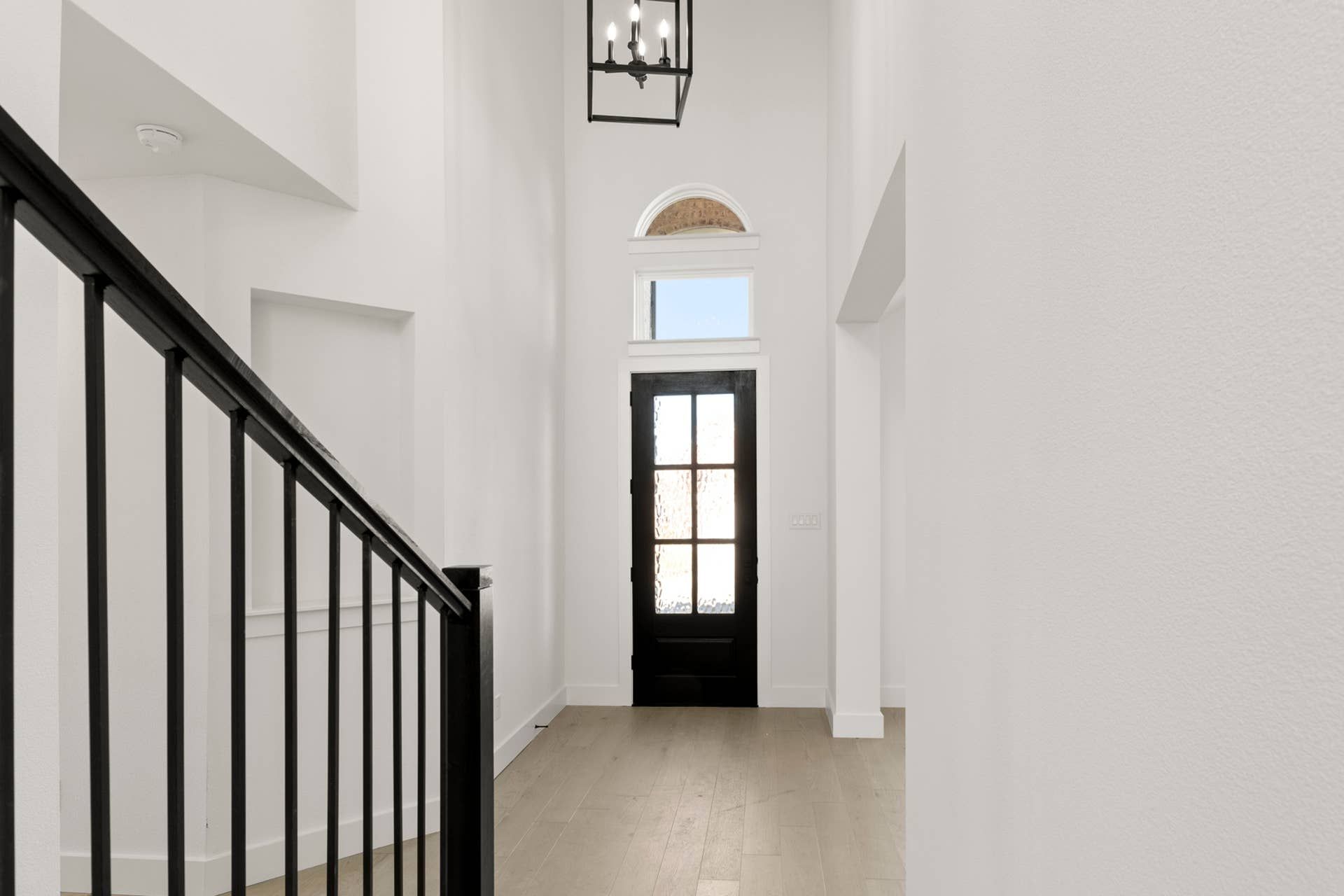 Sleek modern entryway with black door and elegant staircase.