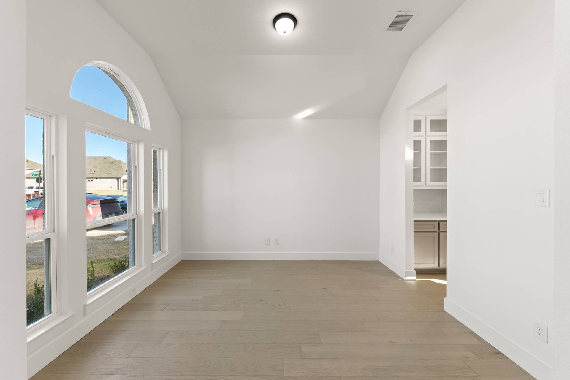 Bright dining room with large arched window and wood flooring.