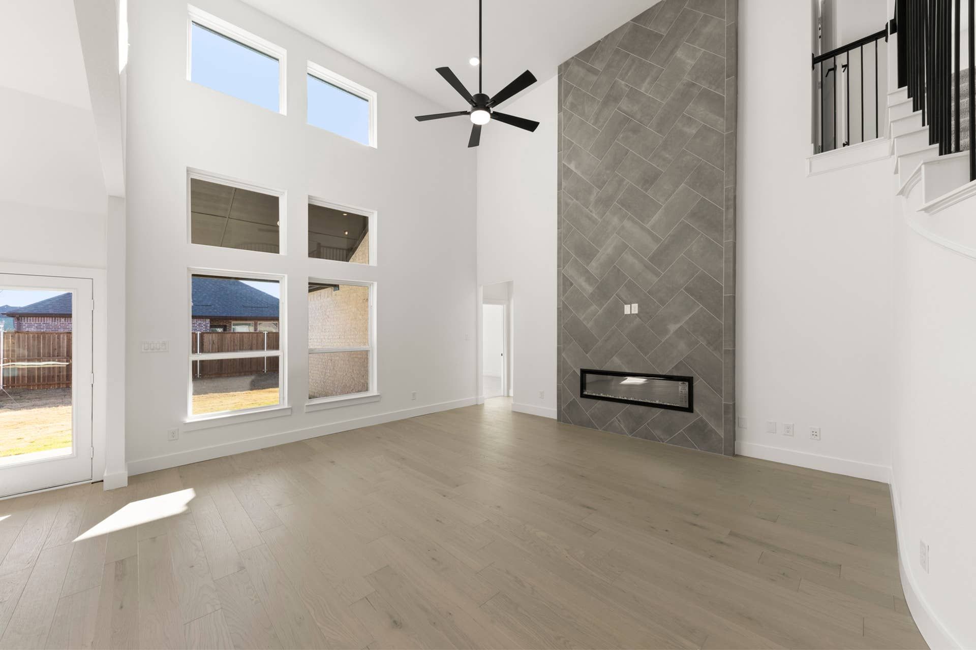 Spacious living room with high ceilings, large windows, and modern fireplace.