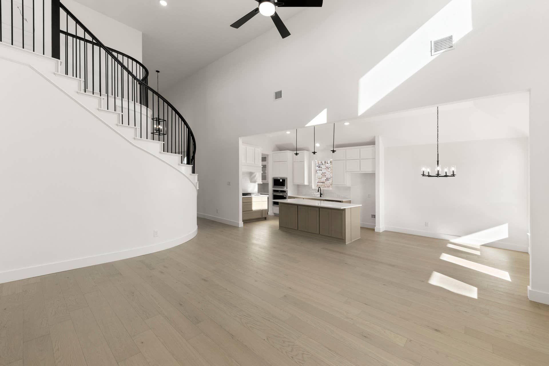 Spacious modern kitchen with open floor plan and elegant curved staircase.