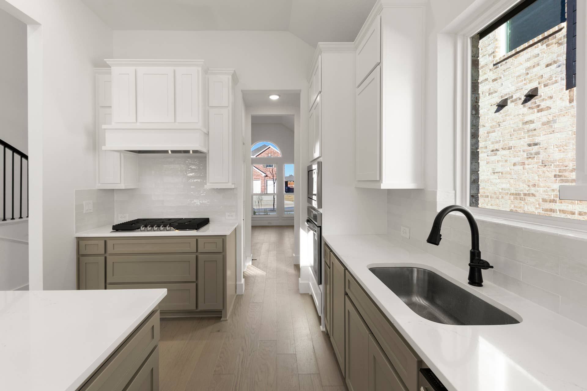 Modern kitchen with white cabinetry, black faucet, and large window view.