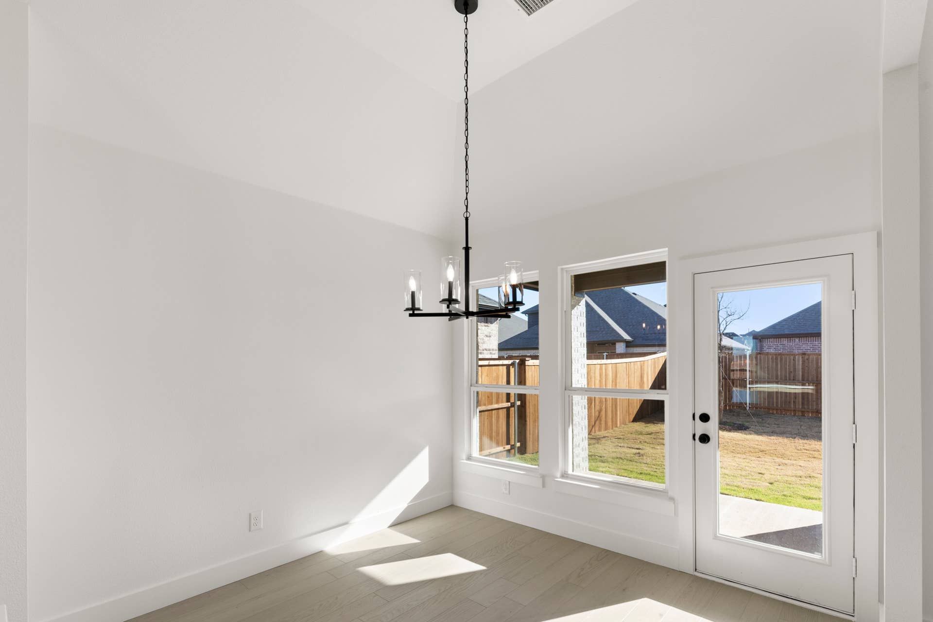 Bright dining nook with large windows and modern chandelier.