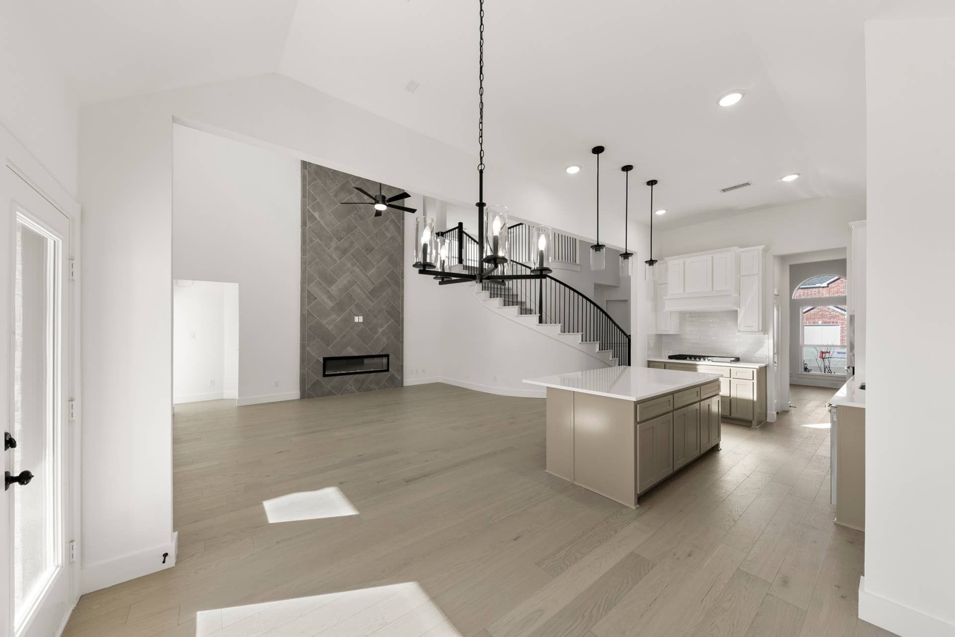 Spacious open-concept living area with modern kitchen and elegant staircase.