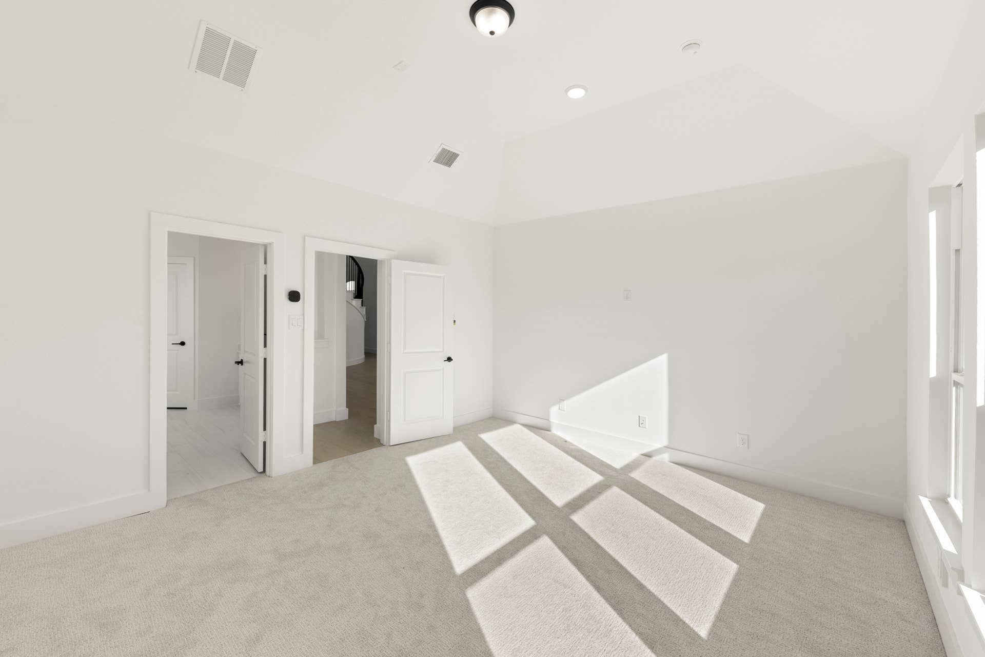 Bright primary bedroom with carpet, white doors, and ample natural light.