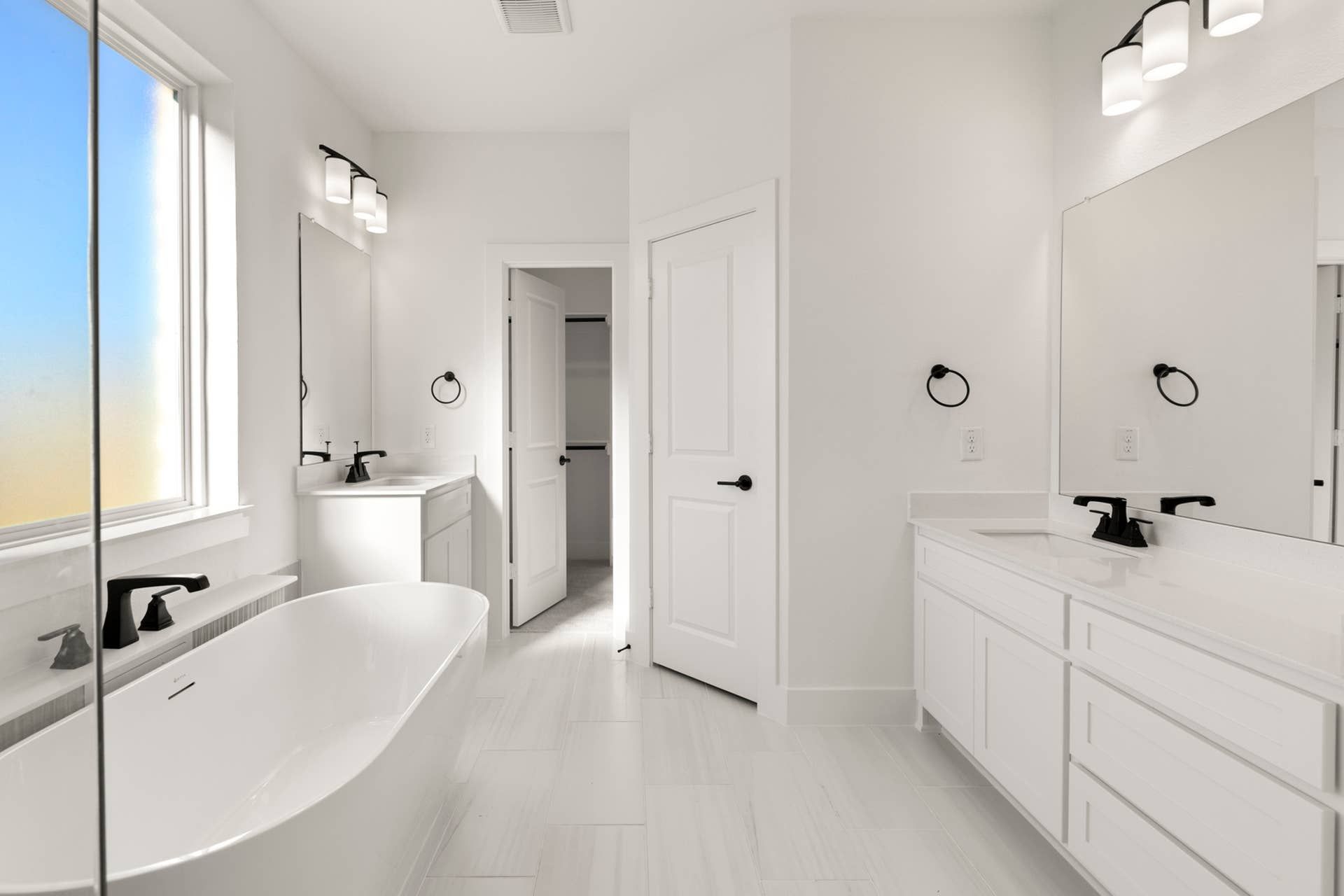 Modern bathroom with freestanding tub, dual sinks, and large mirrors.
