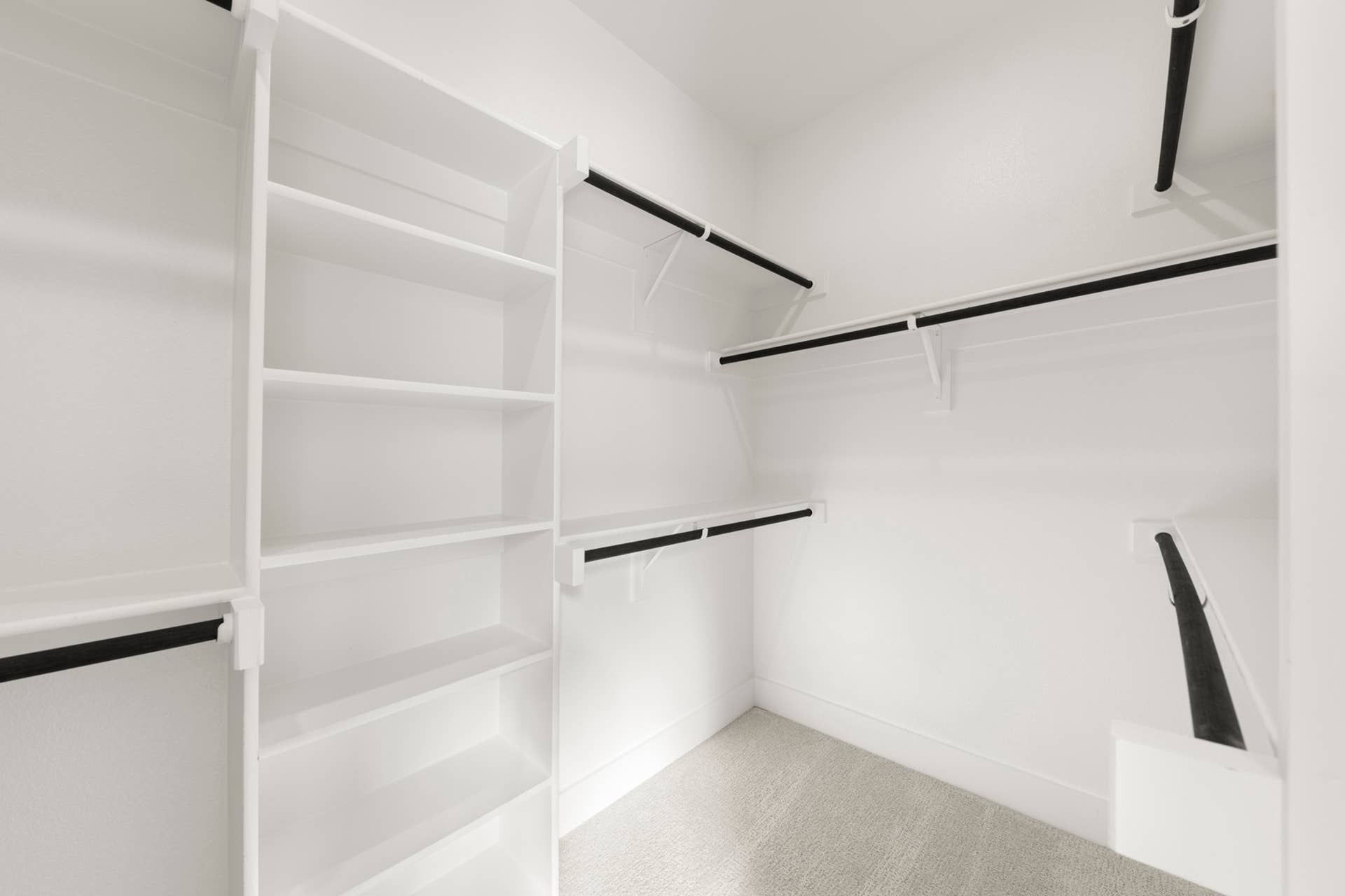 Spacious walk-in closet with white shelving and hanging rods.