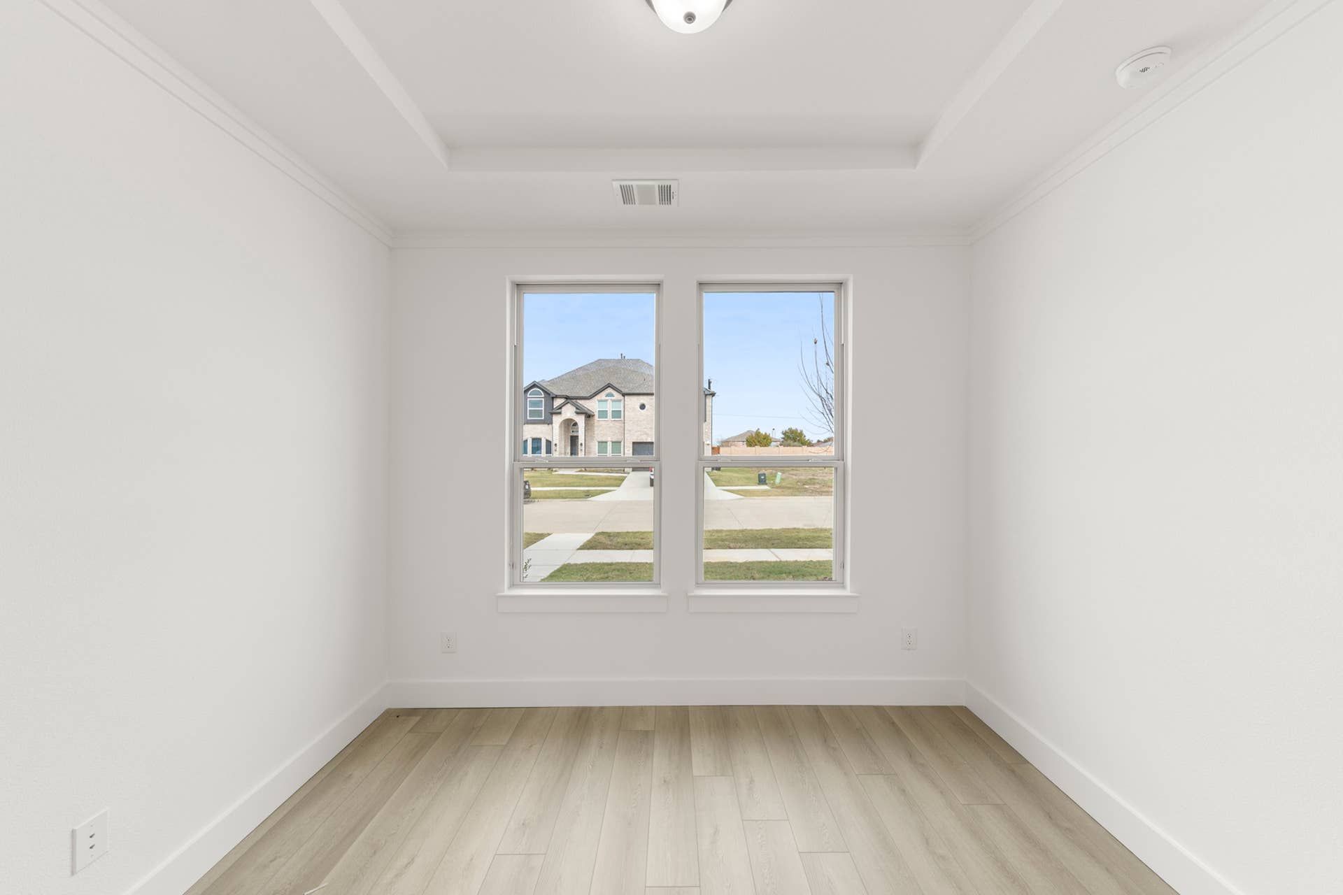 Bright study room with large windows and hardwood flooring.