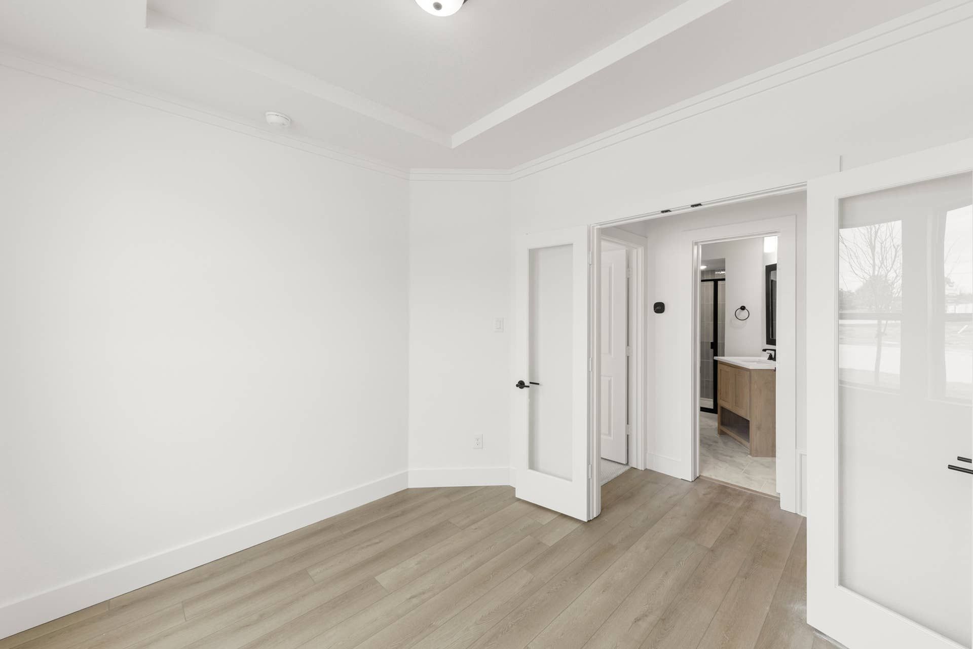 Modern study room with light wood flooring and glass-paned double doors.