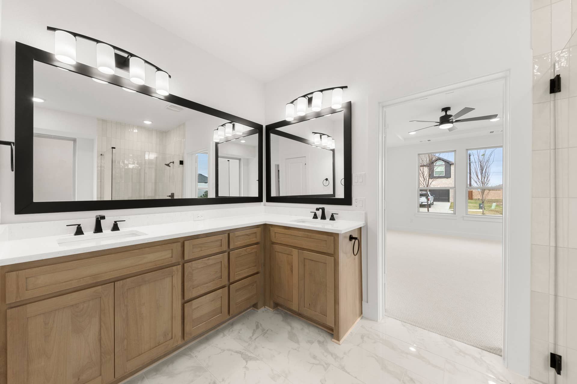Modern bathroom with double vanity, large mirrors, and natural wood cabinetry.