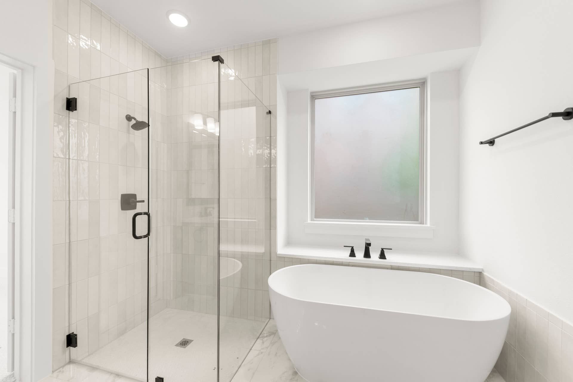 Elegant bathroom with glass shower and freestanding bathtub.