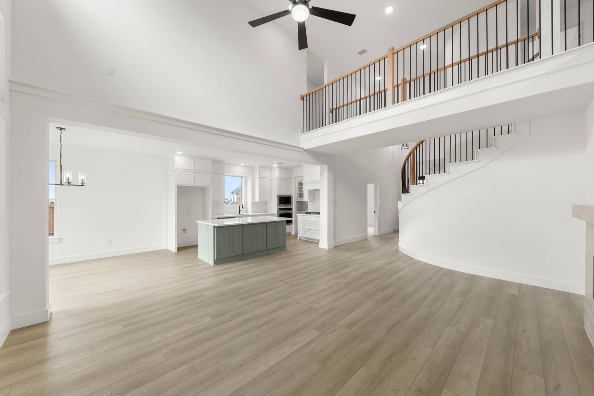 Spacious open-concept living area with modern kitchen and elegant spiral staircase.