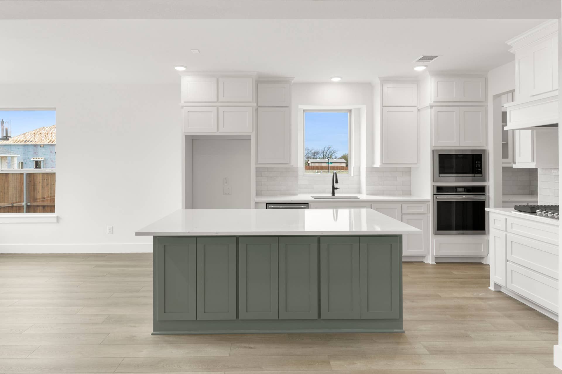 Modern kitchen with white cabinetry, island, and stainless steel appliances.