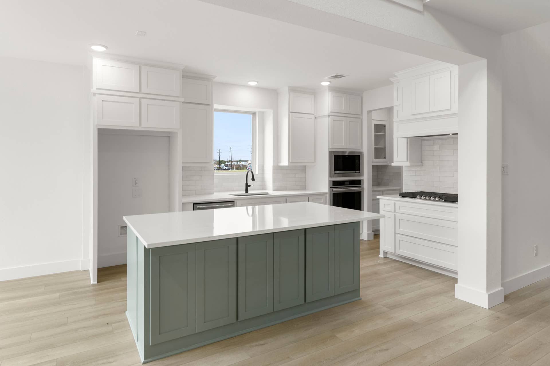 Modern kitchen with white cabinetry, island, and stainless steel appliances.