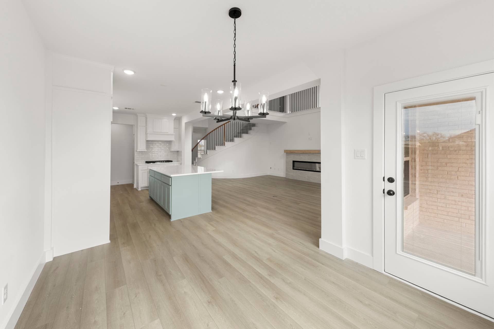 Spacious open-concept dining area with modern chandelier and light wood flooring.