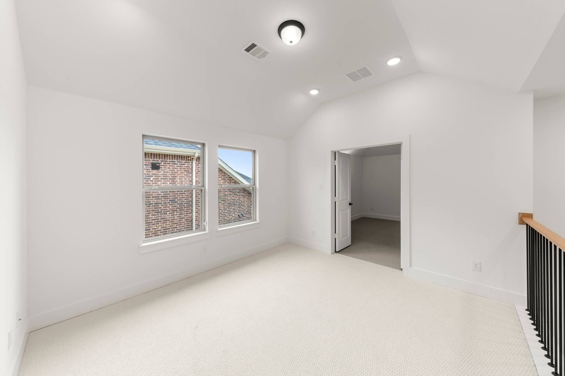 Bright, spacious room with large windows and neutral carpeting.
