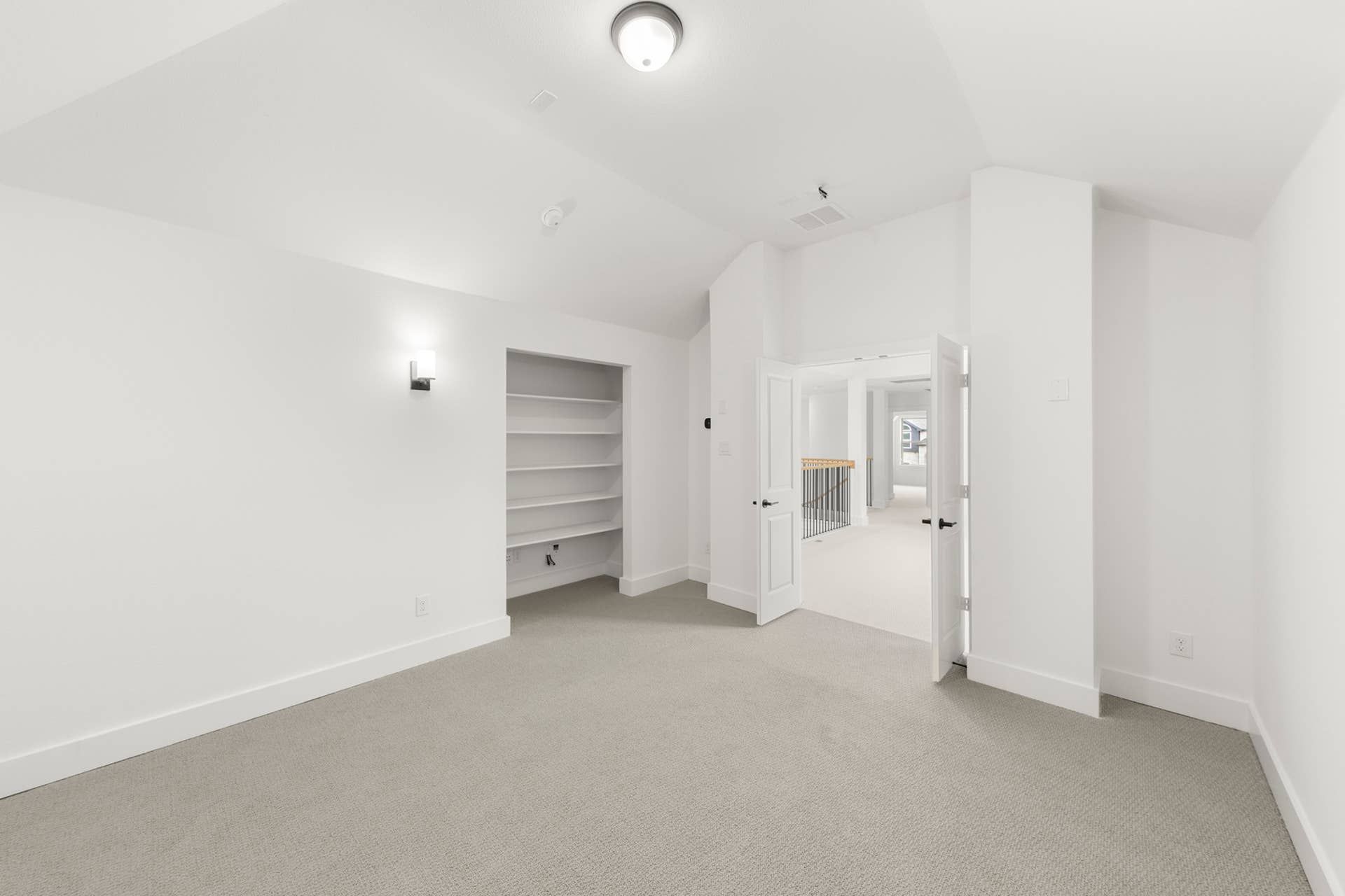 Bright interior room with built-in shelves and double doors leading to hallway.