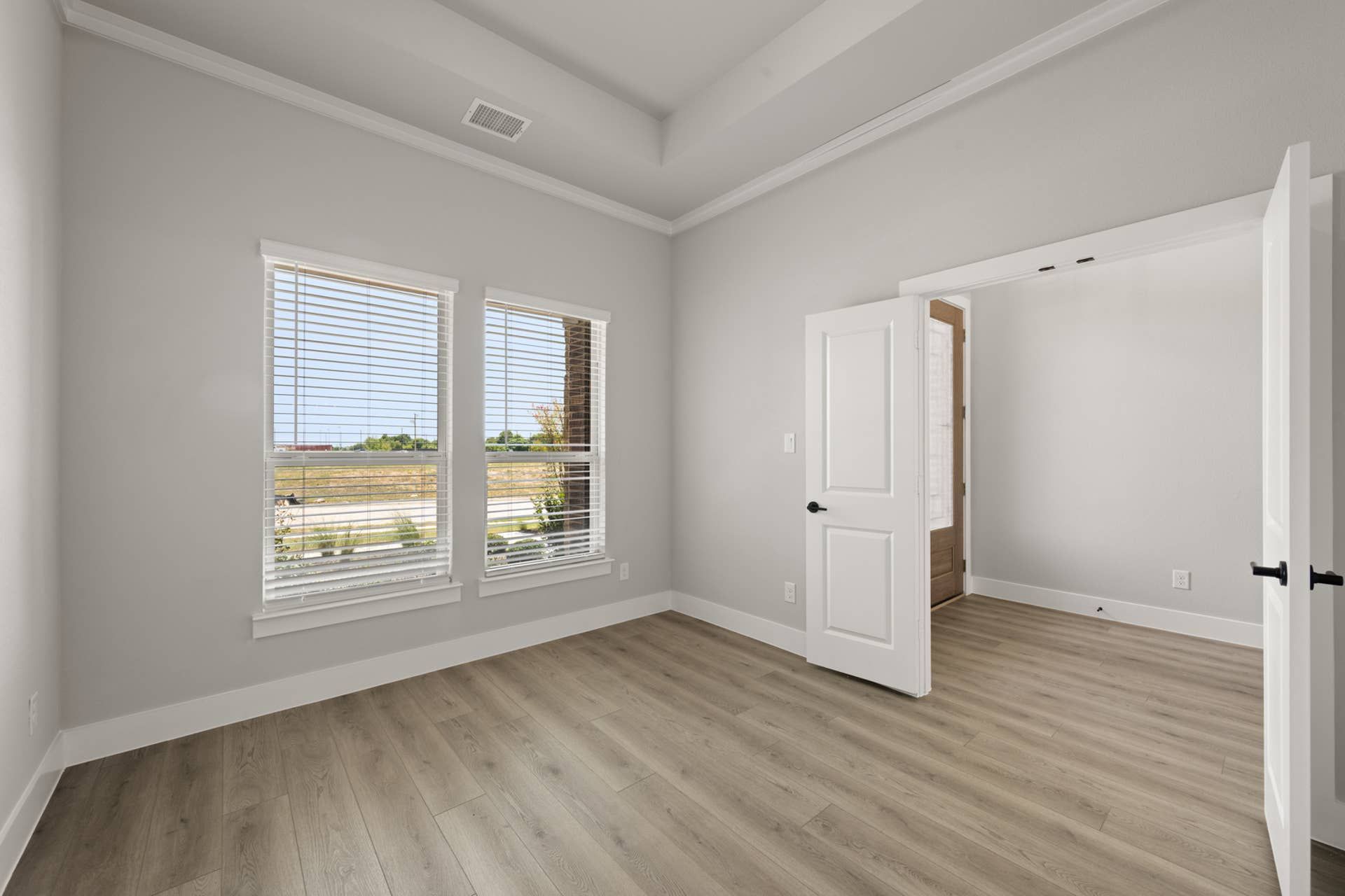 Bright study room with large windows and wood flooring.