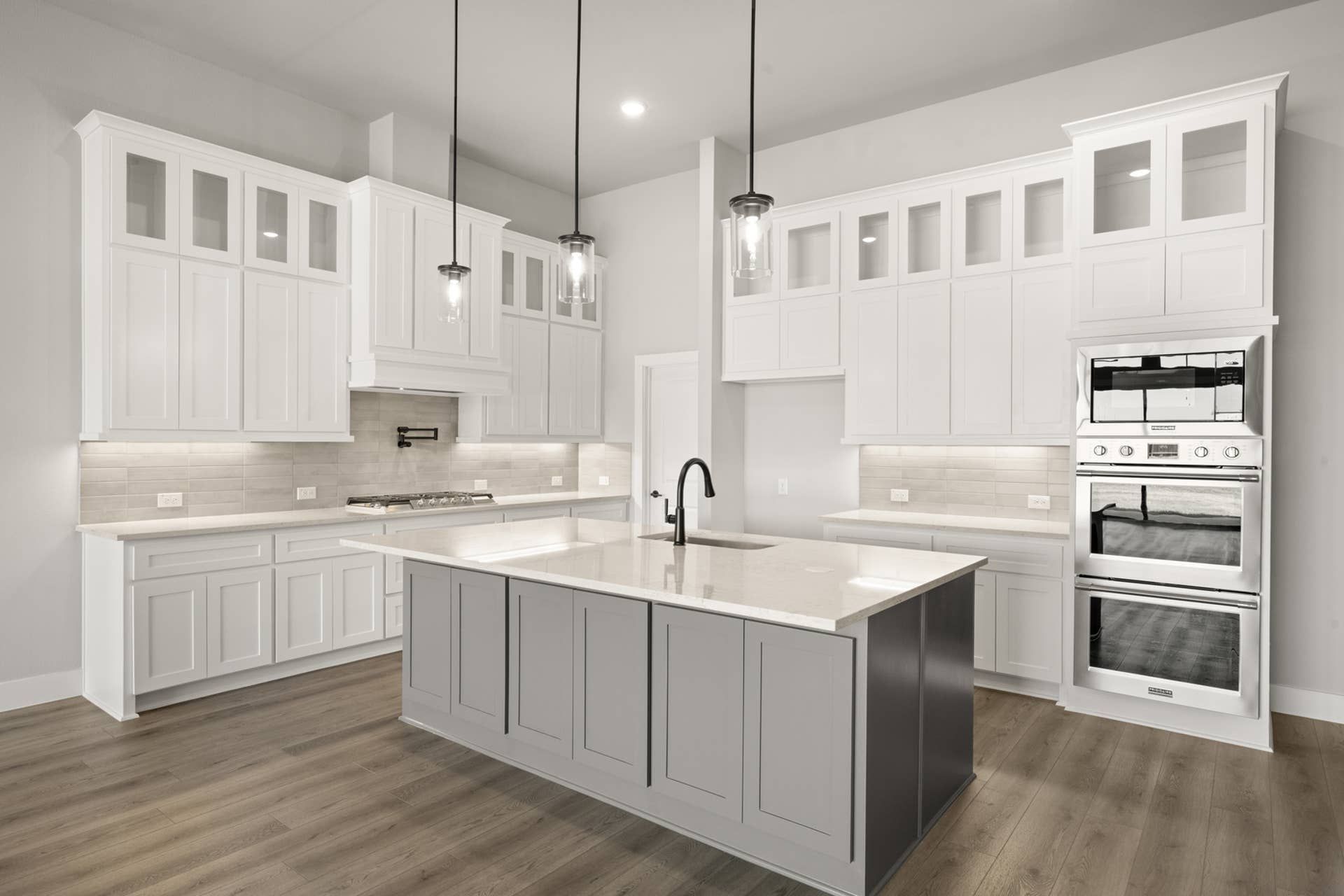 Modern kitchen with white cabinetry, large island, and stainless steel appliances.