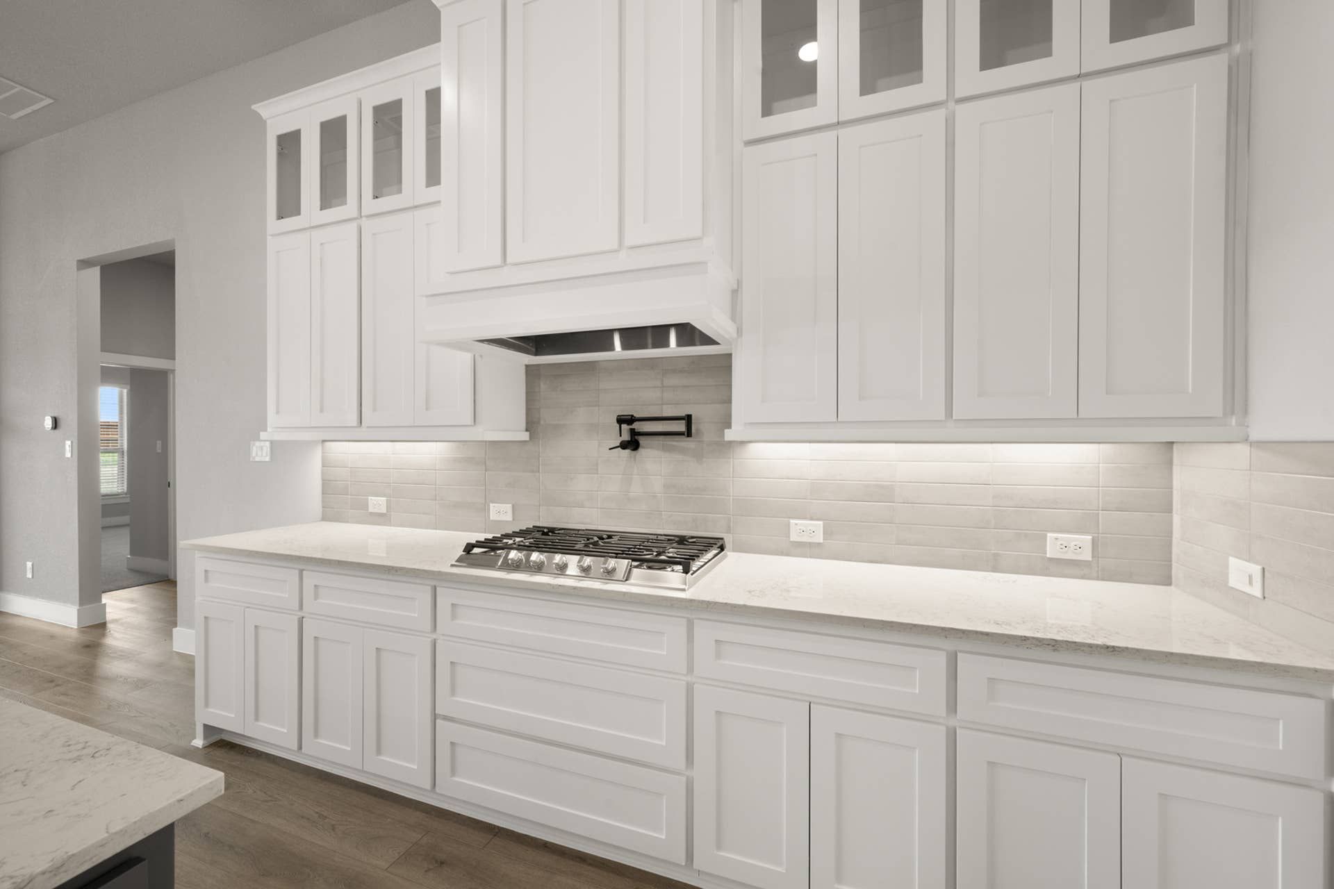 Modern kitchen with white cabinetry, gas stovetop, and tiled backsplash.