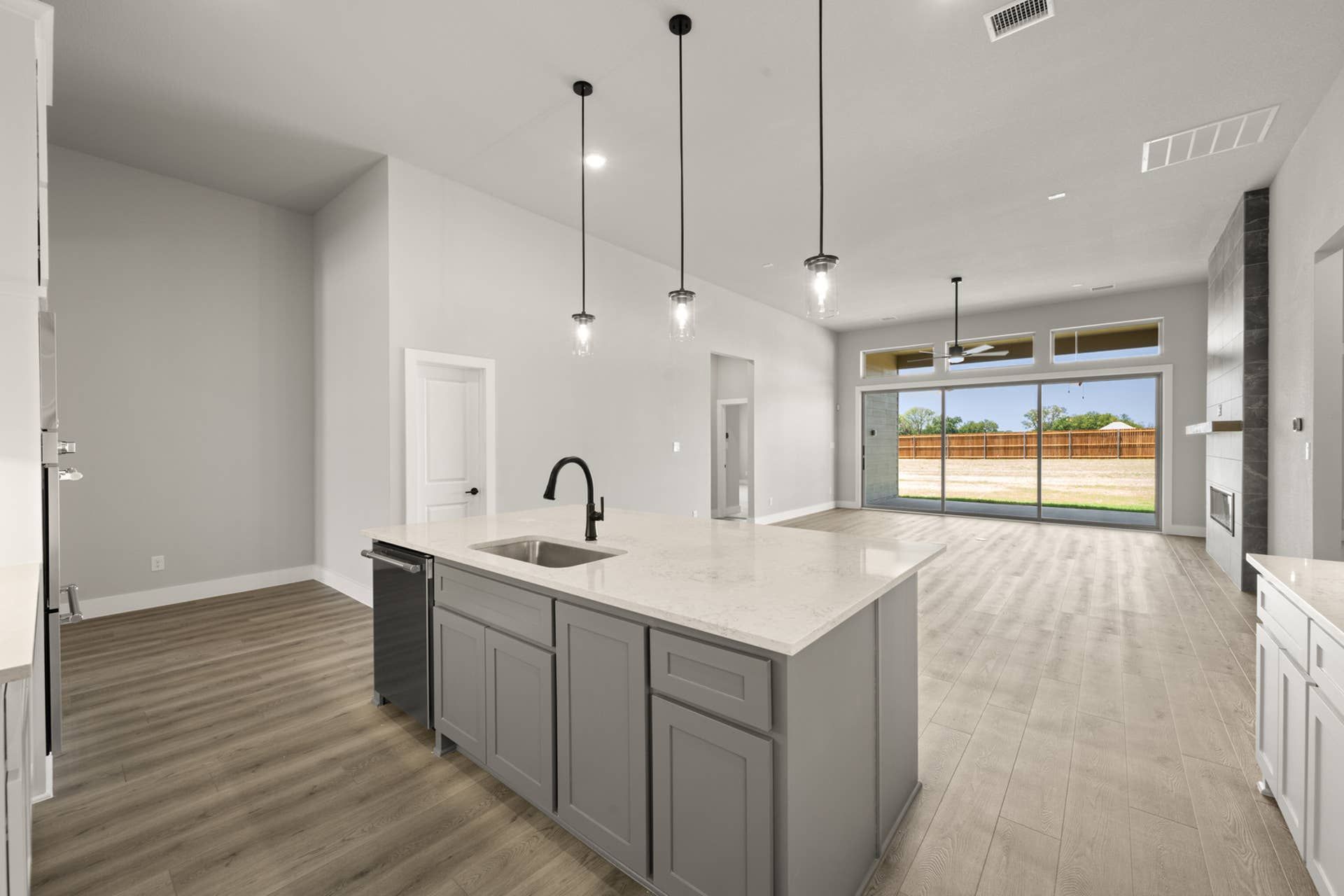 Modern kitchen with island, pendant lights, and open living space.