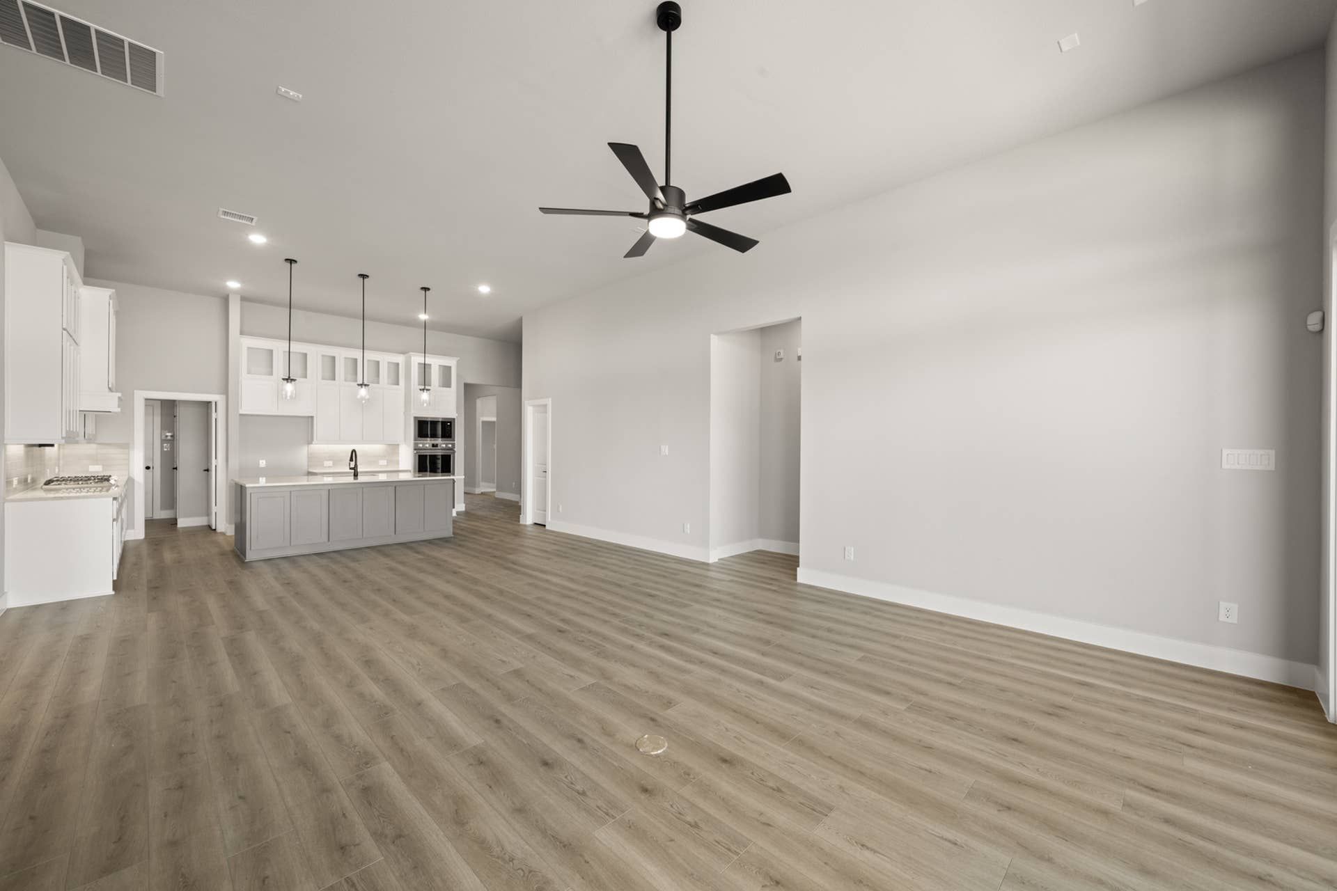 Modern open-concept living area with kitchen island and ceiling fan.