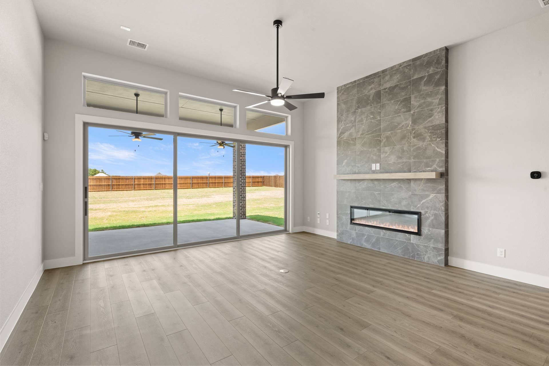 Modern living room with large windows, sleek fireplace, and ceiling fan.