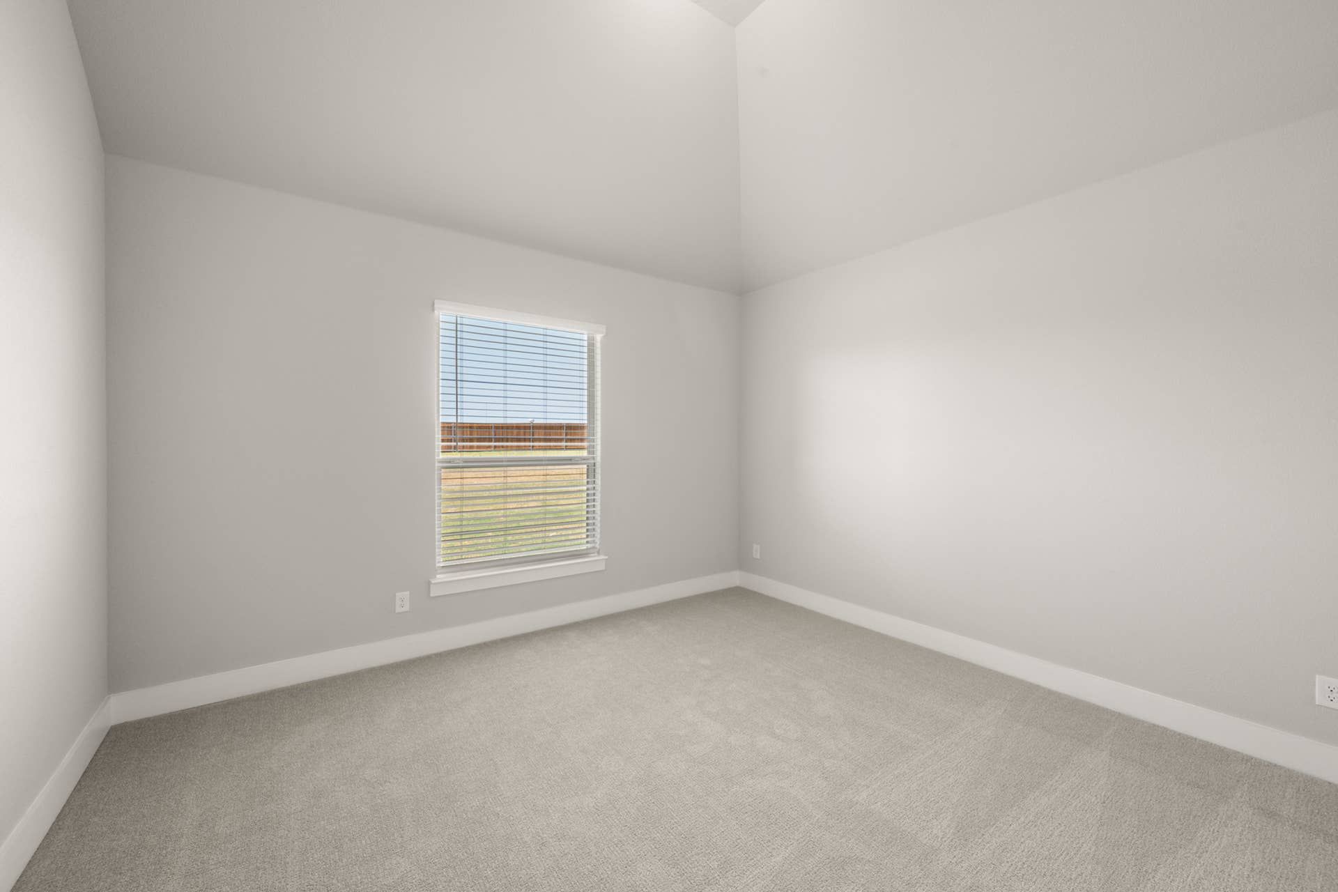 Spacious bedroom with neutral carpet and single window with blinds.