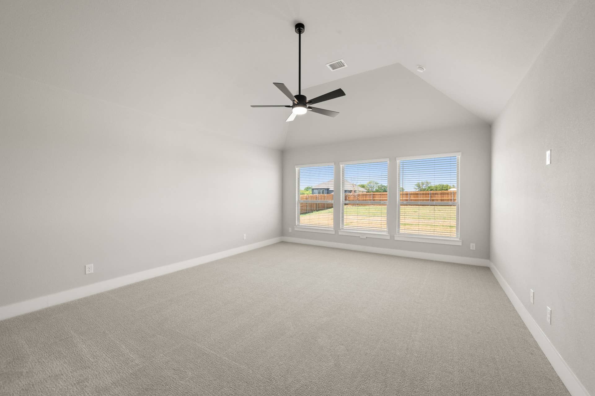 Spacious primary suite with large windows and ceiling fan.
