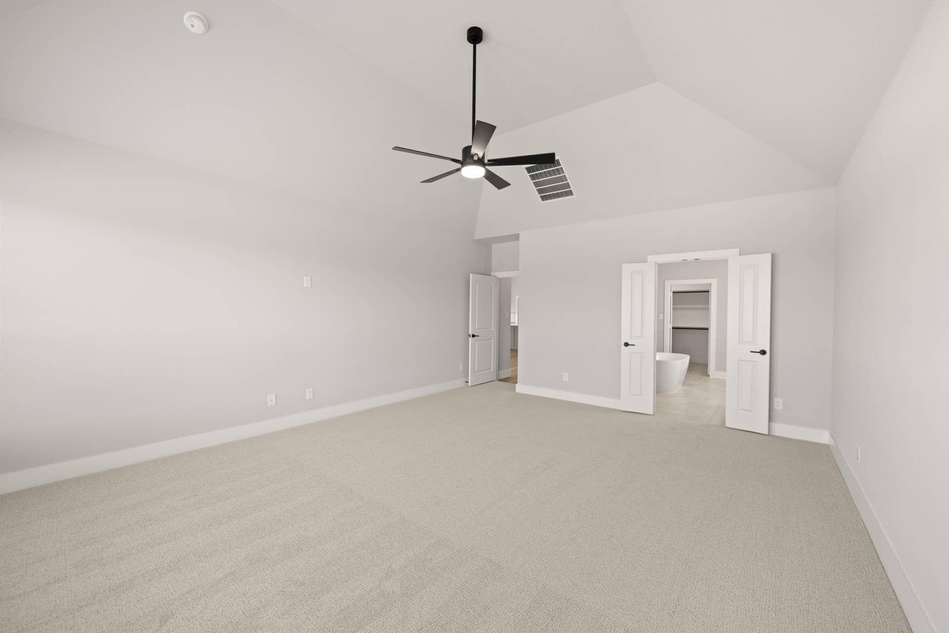 Spacious primary suite with vaulted ceiling and modern ceiling fan.