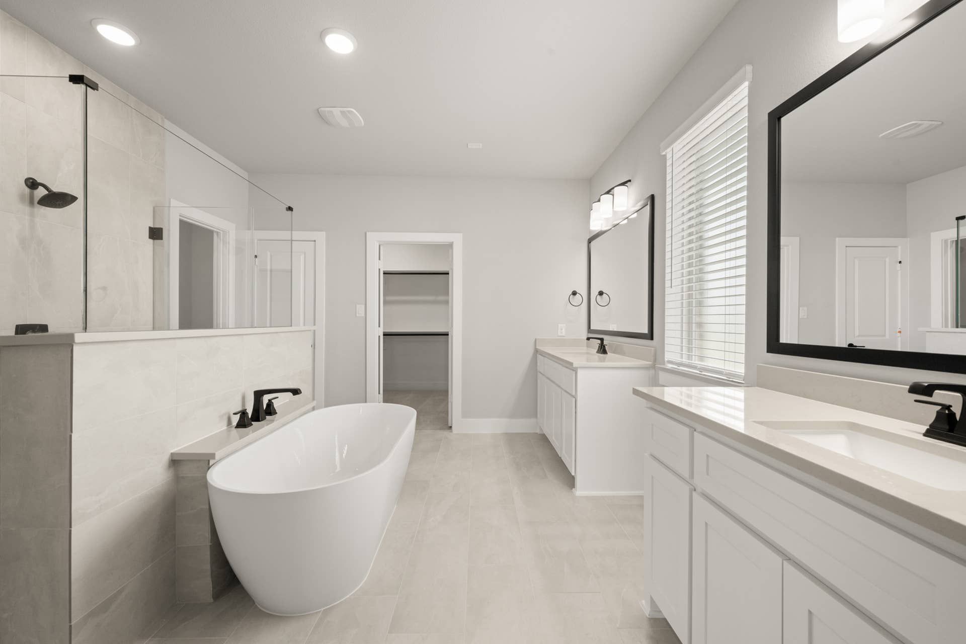 Luxurious bathroom with freestanding tub, double vanity, and walk-in closet entry.